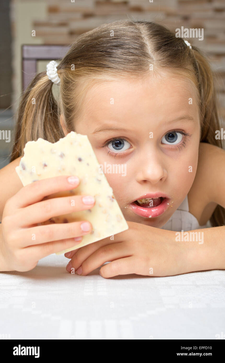 Kleines Mädchen eine Schokolade zu essen, am Tisch Stockfoto