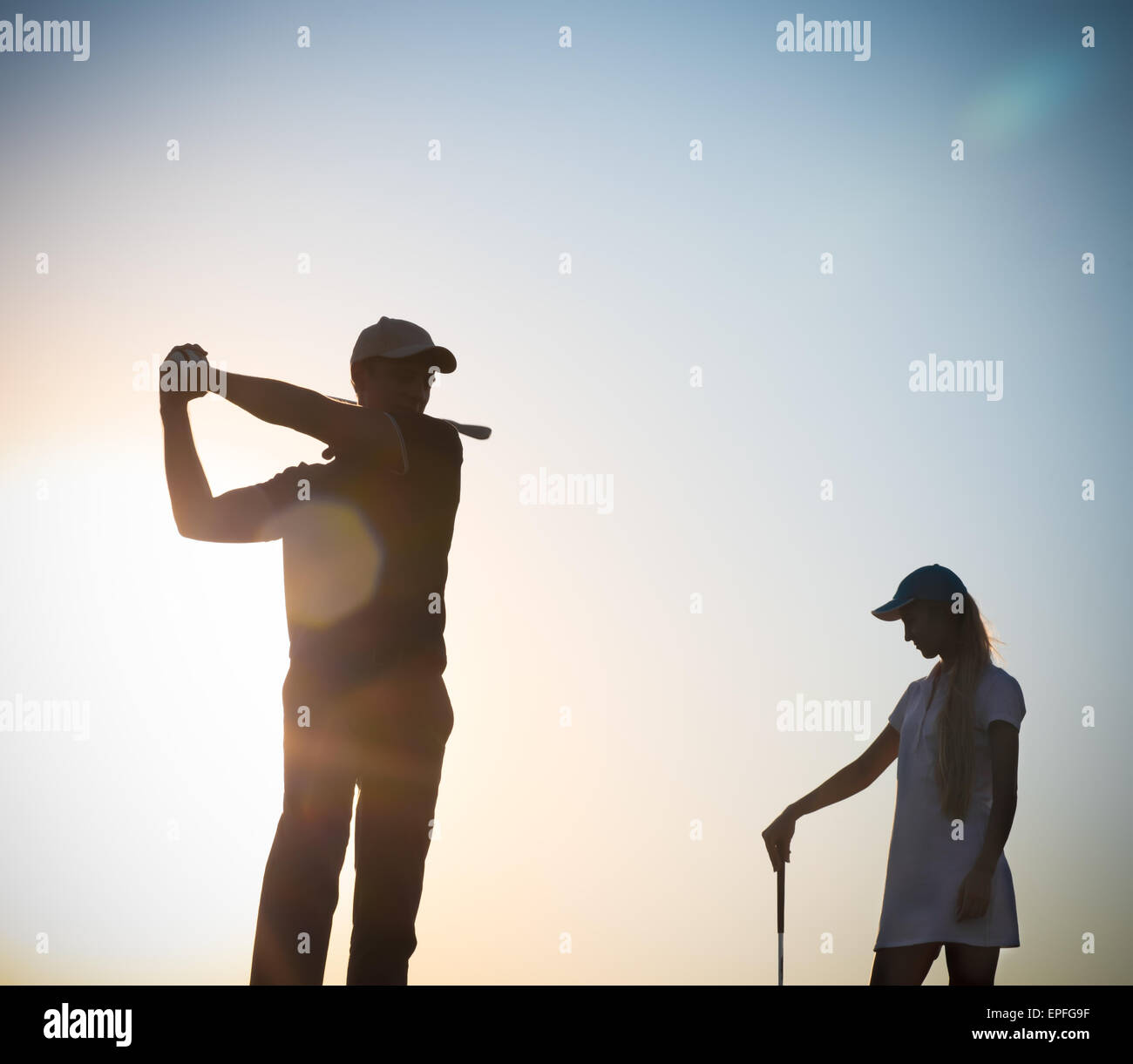 Männliche und weibliche Golfer bei Sonnenuntergang Stockfoto