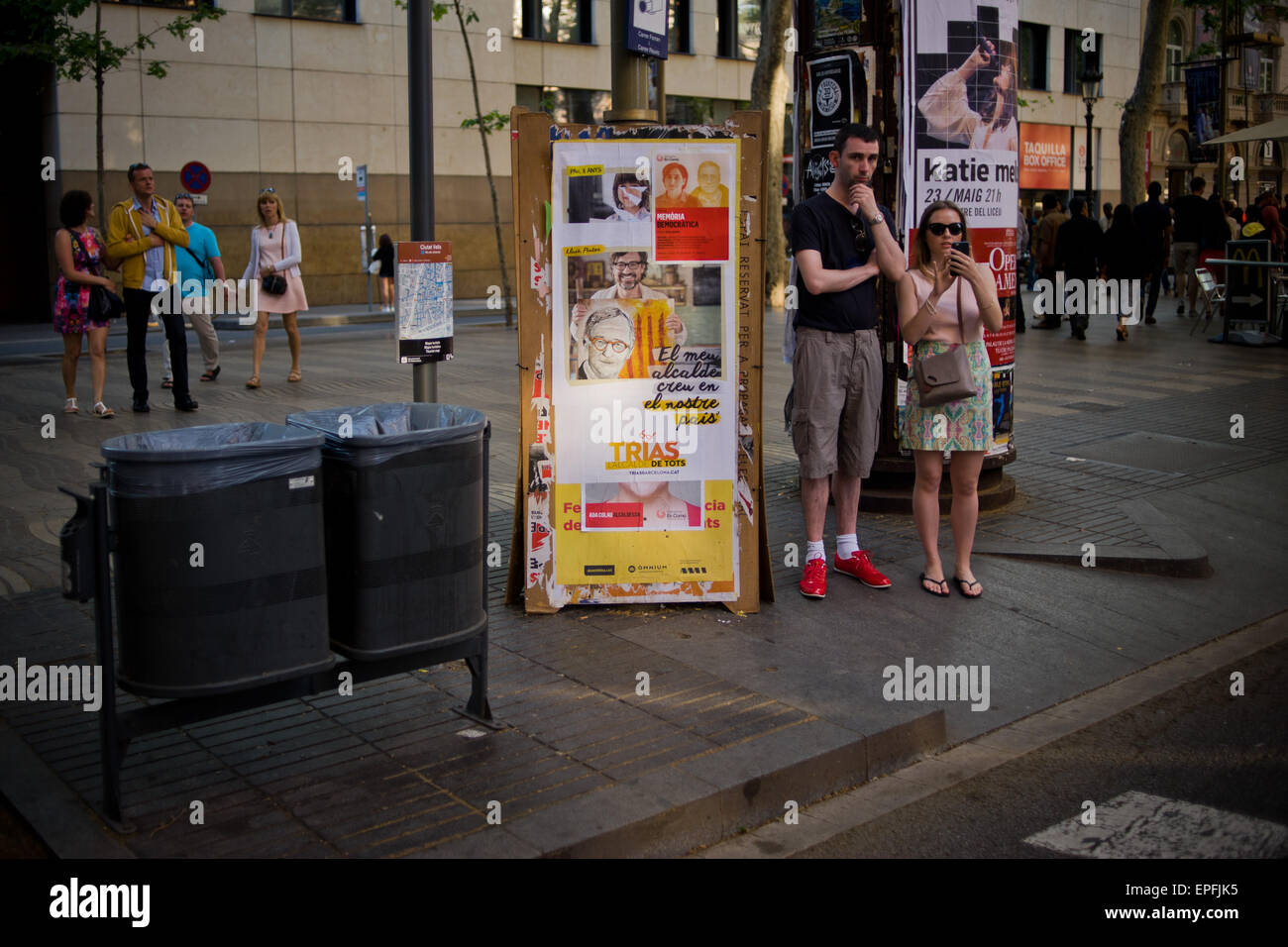 Ein paar Touristen befinden sich neben einem Zaun Wahlpropaganda in Barcelona. Stockfoto