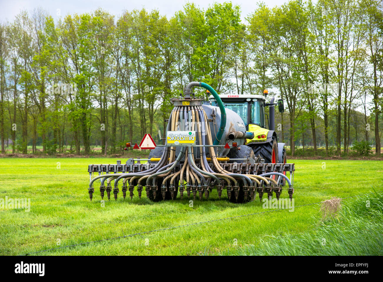 Bauernhof mit Gülle Spritzgießmaschine hinter Traktor Stockfoto