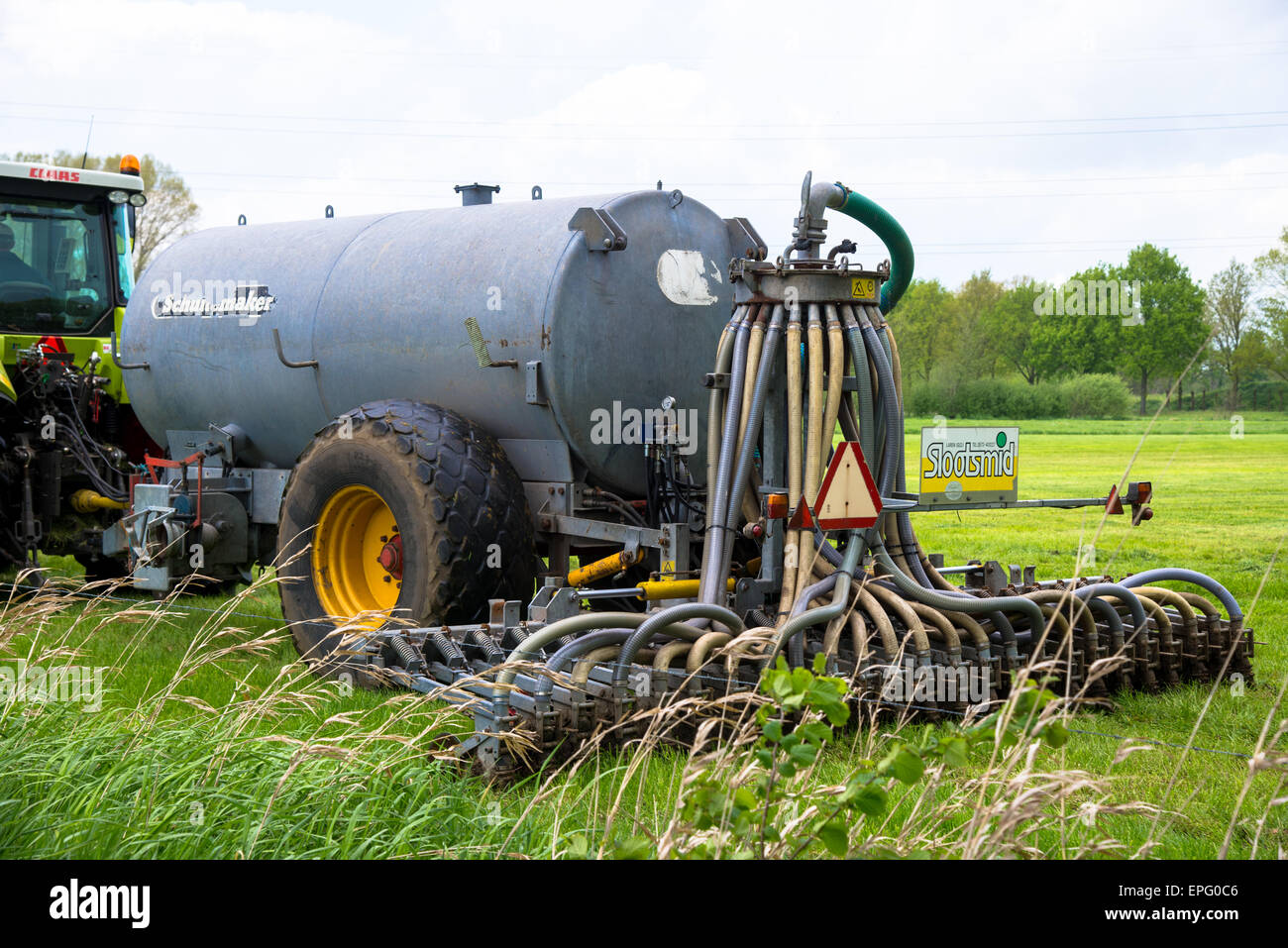 Bauernhof mit Gülle Spritzgießmaschine hinter Traktor Stockfoto