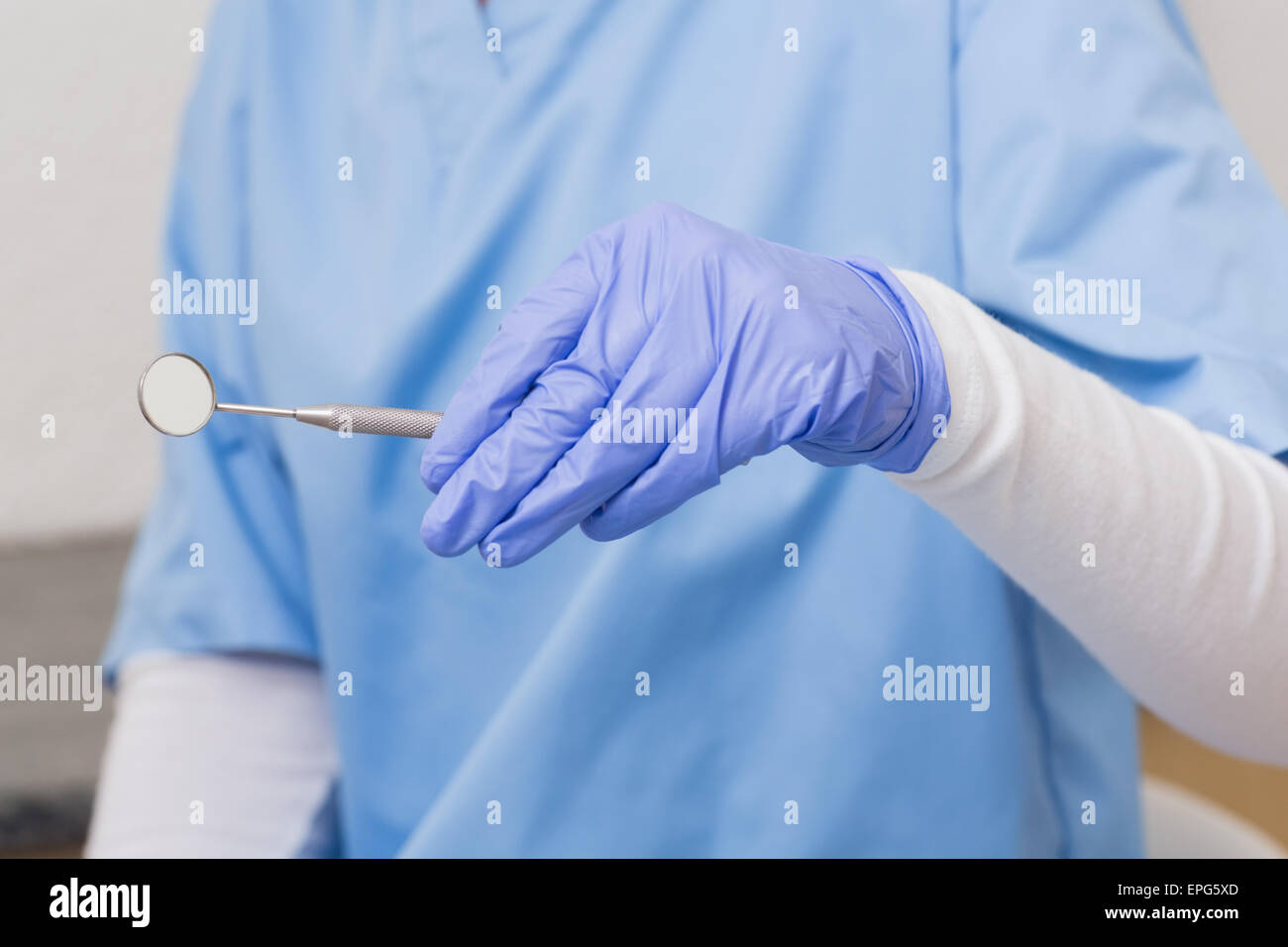 Zahnarzt in blau scheuert sich mit abgewinkelten Spiegel Stockfoto