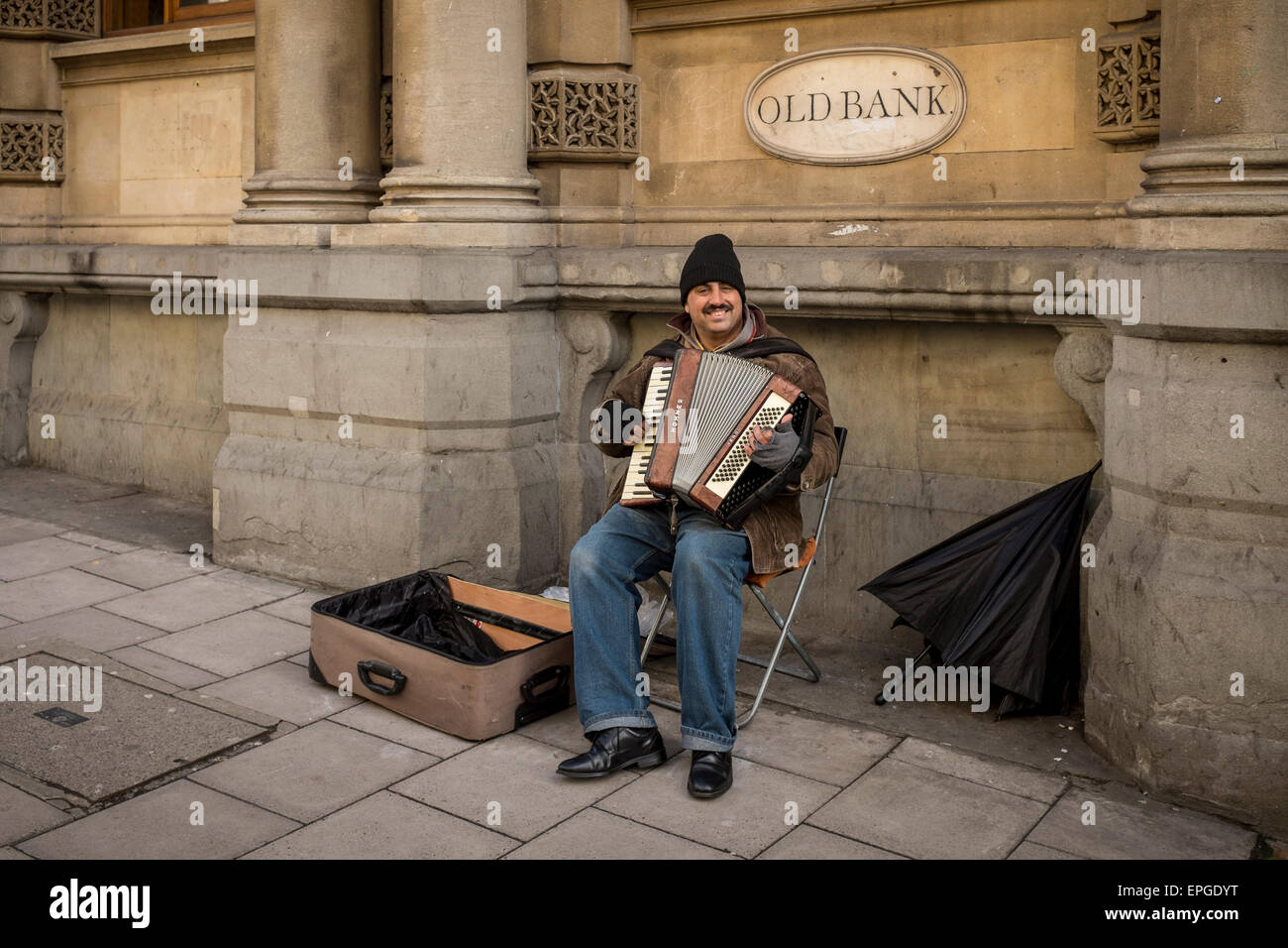 Straßenmusiker spielen Akkordeon vor einem alten Bankgebäude, Bristol, UK Stockfoto