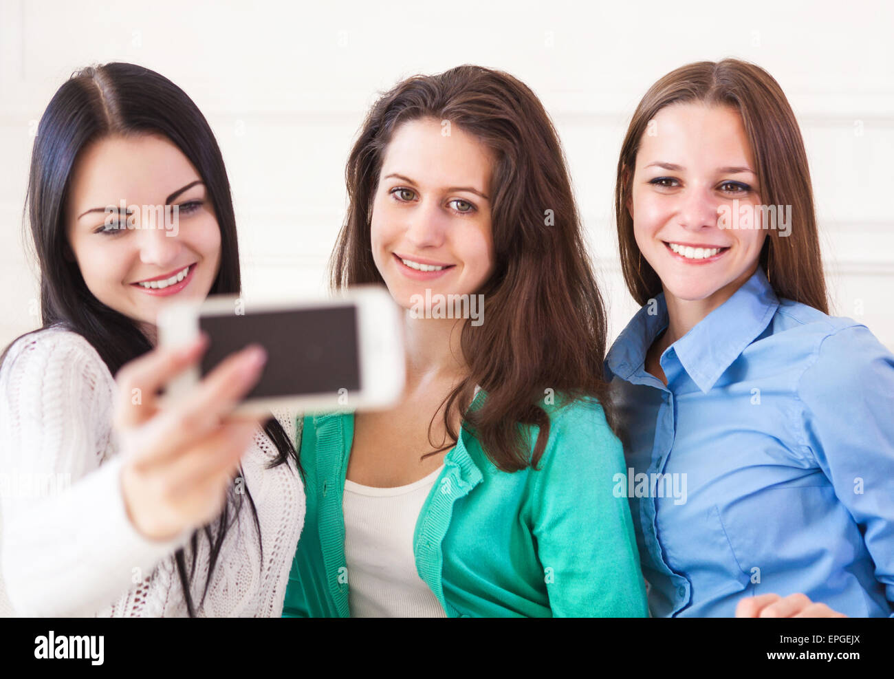 Drei lächelnde Mädchen im Teenageralter unter Selfie mit Smartphone-Kamera zu Hause Stockfoto