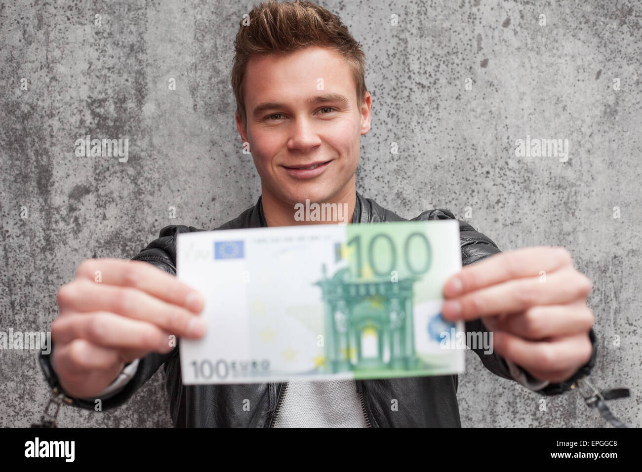 Lässige junge Mann hält 100-Euro-Schein Stockfoto