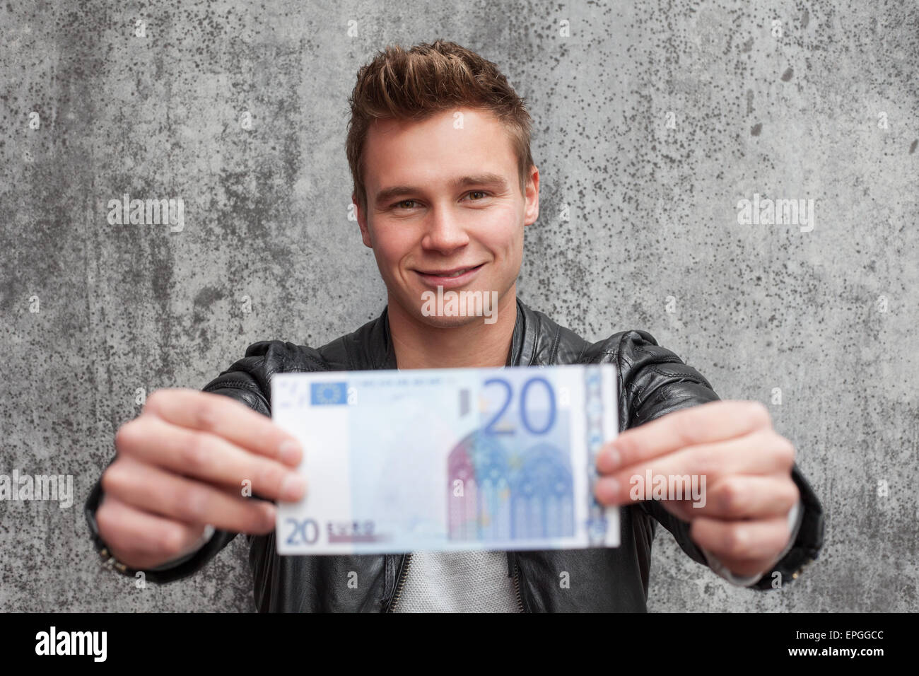 Lässige junge Mann hält 20-Euro-Schein Stockfoto