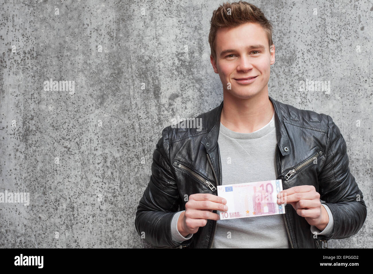 Lässige junge Mann hält 10 euro Stockfoto
