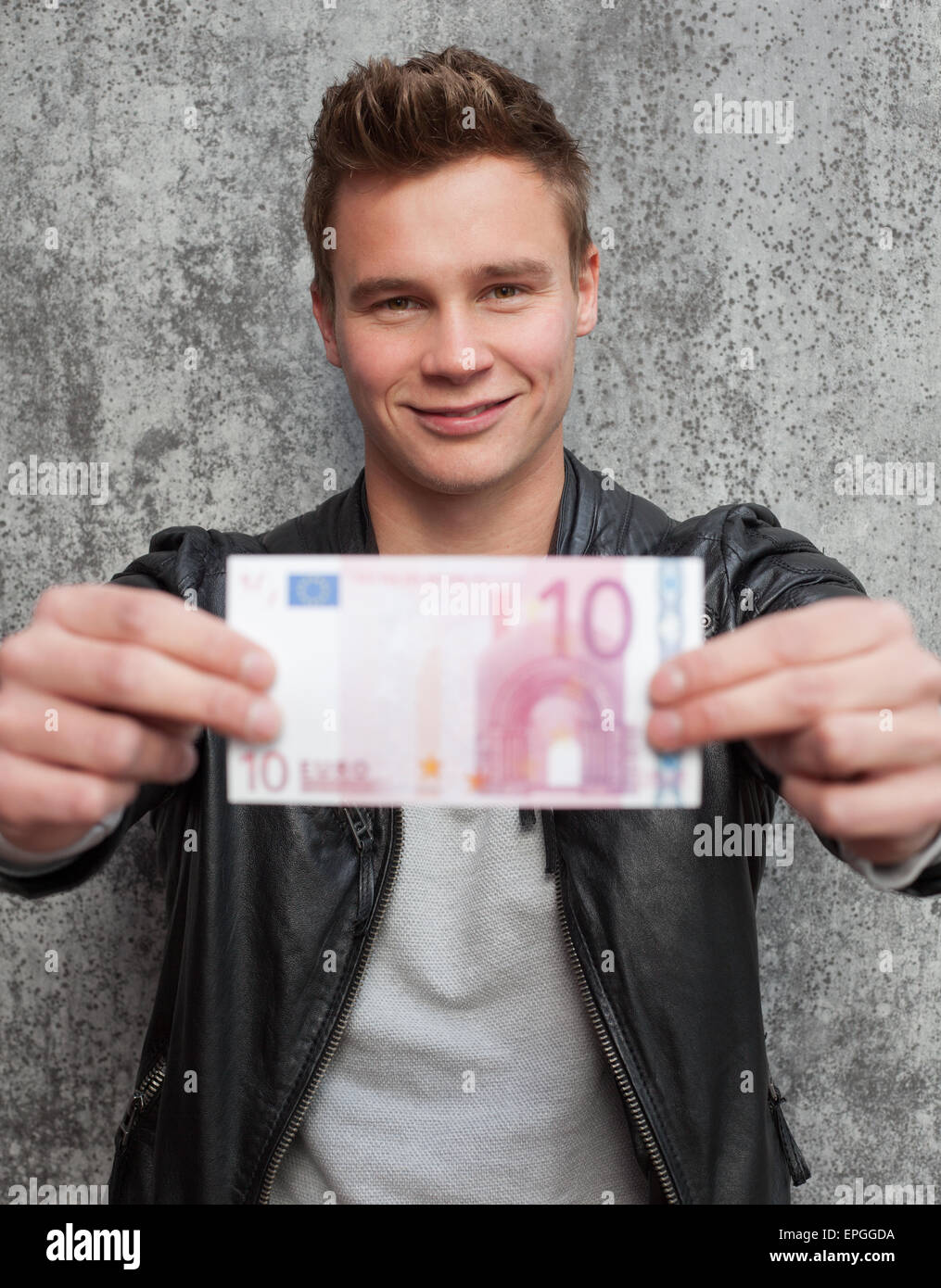 Lässige junge Mann hält zehn-Euro-Schein Stockfoto