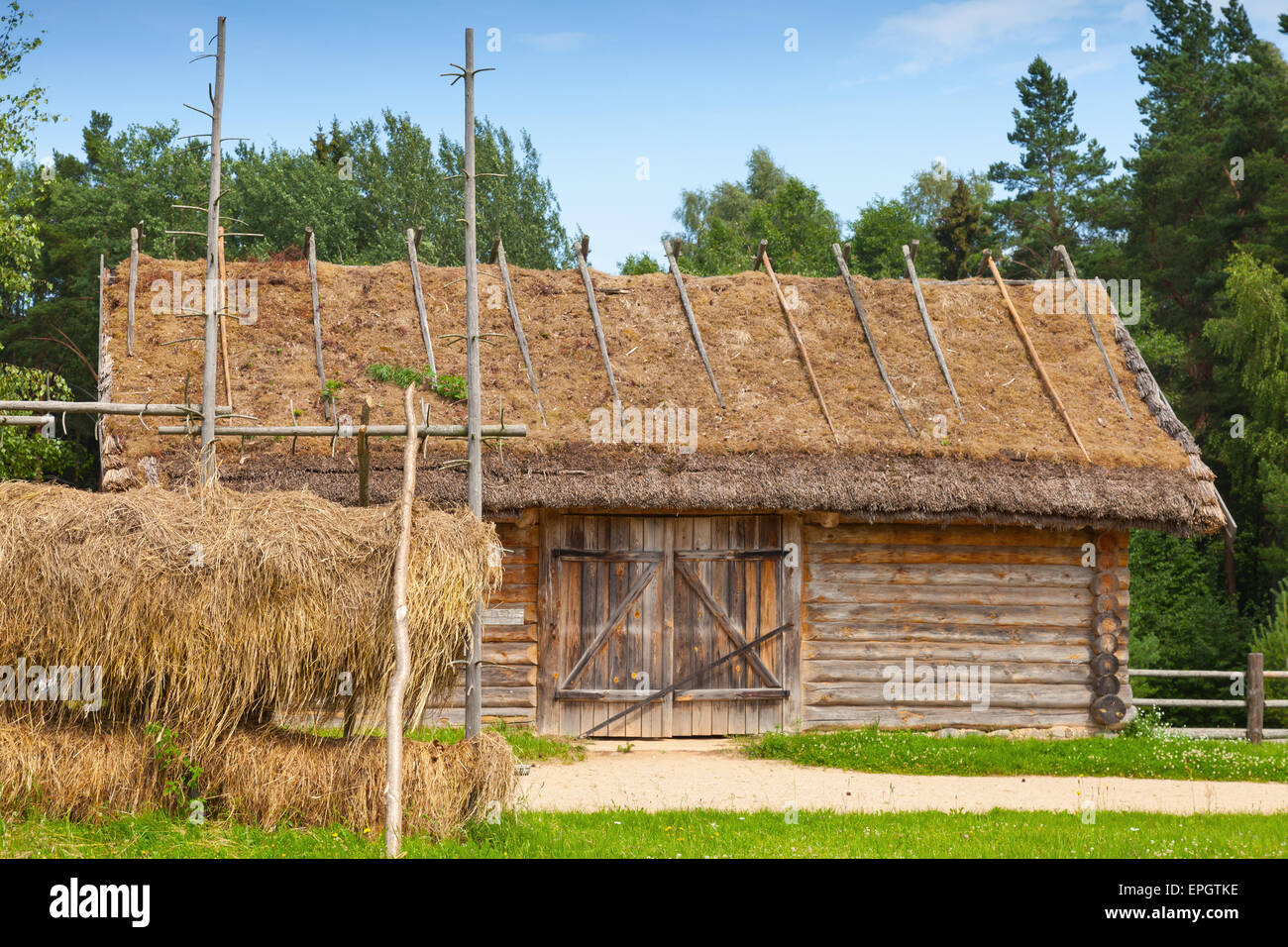 Russische ländliche Holzbaukunst beispielsweise im freien Heu trocknen in der Nähe von alte hölzerne Scheune mit verschlossenen Tor Stockfoto