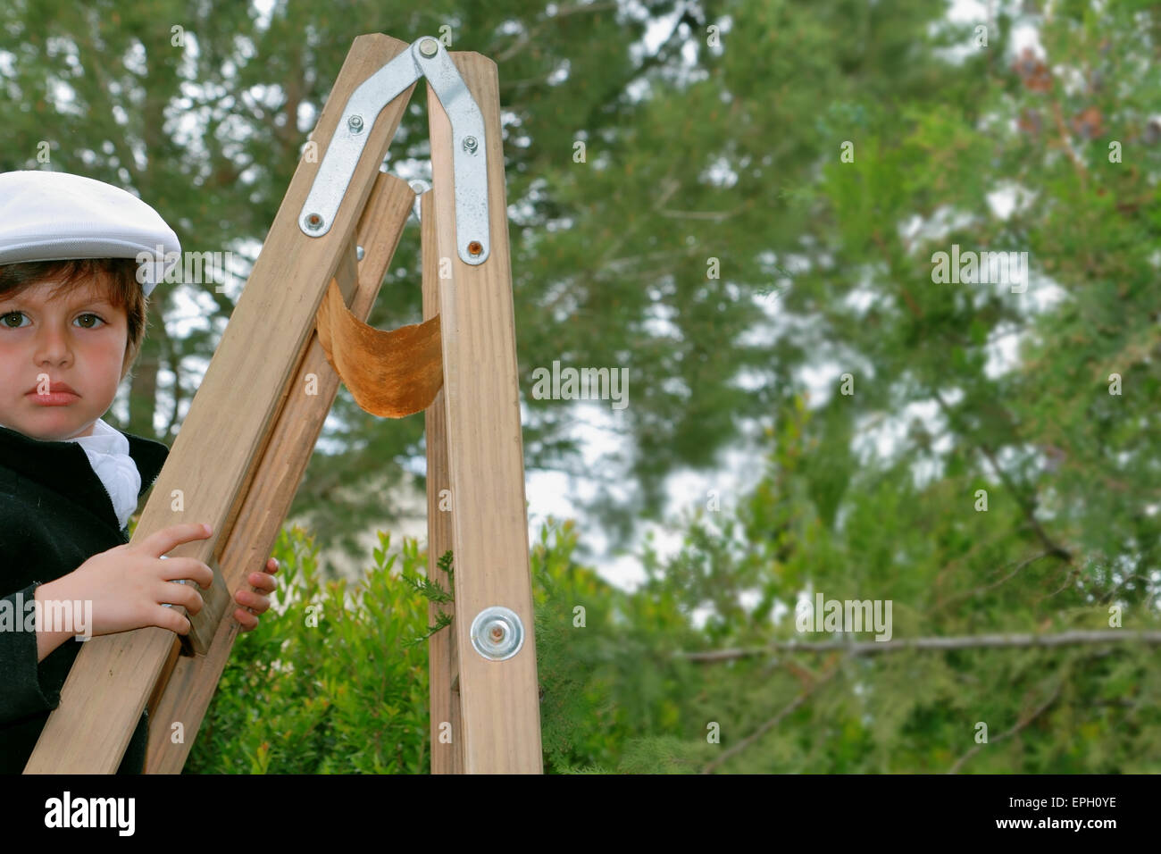 Der charmante junge kletterte auf eine Holzleiter Stockfoto