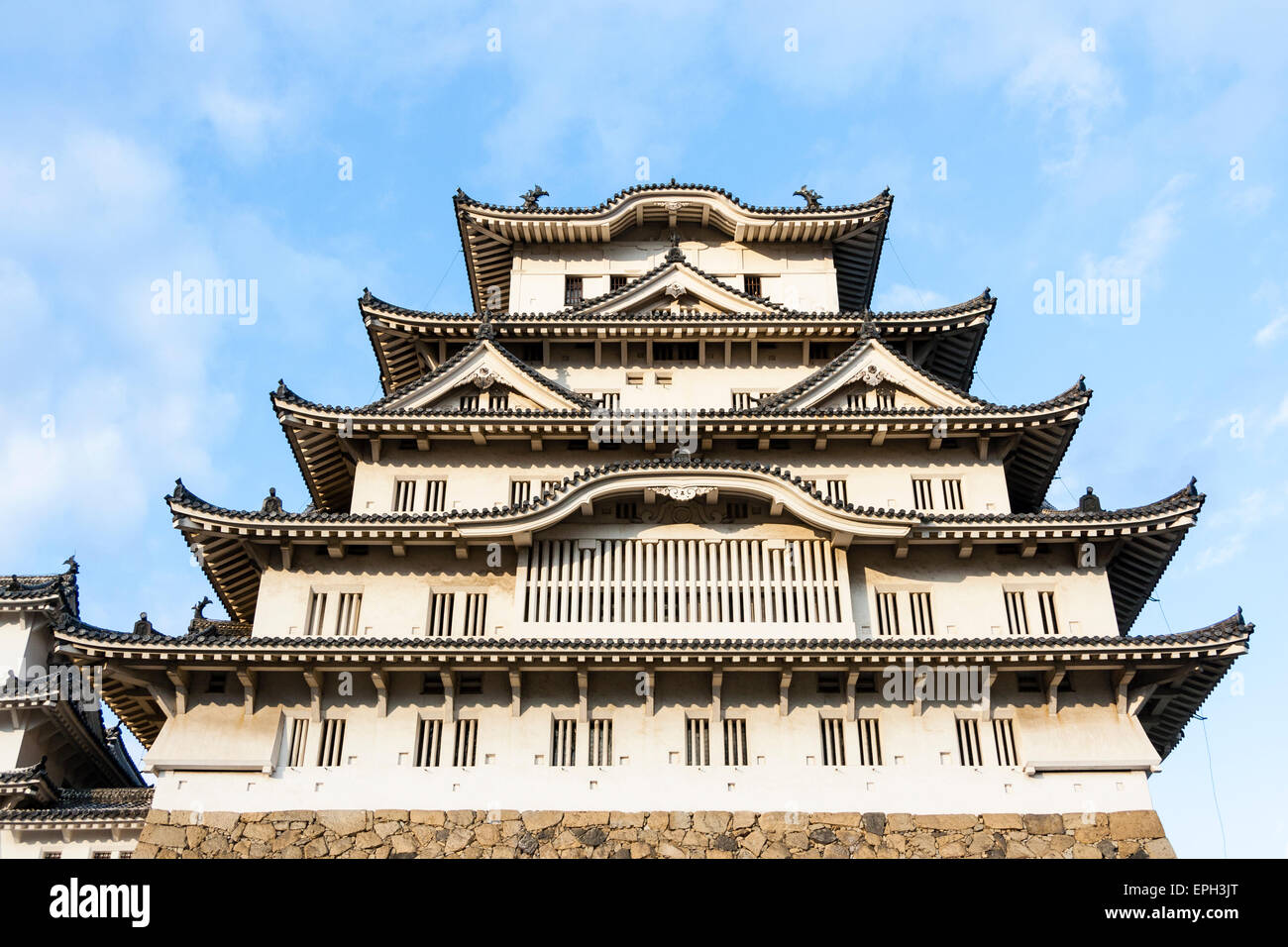 Der sonnenbeleuchtete Borogata-Stil halten des Himeji Schloss in Japan, während der Nachmittag goldene Stunde gegen einen blauen Himmel mit einigen weißen Wolken in. Stockfoto