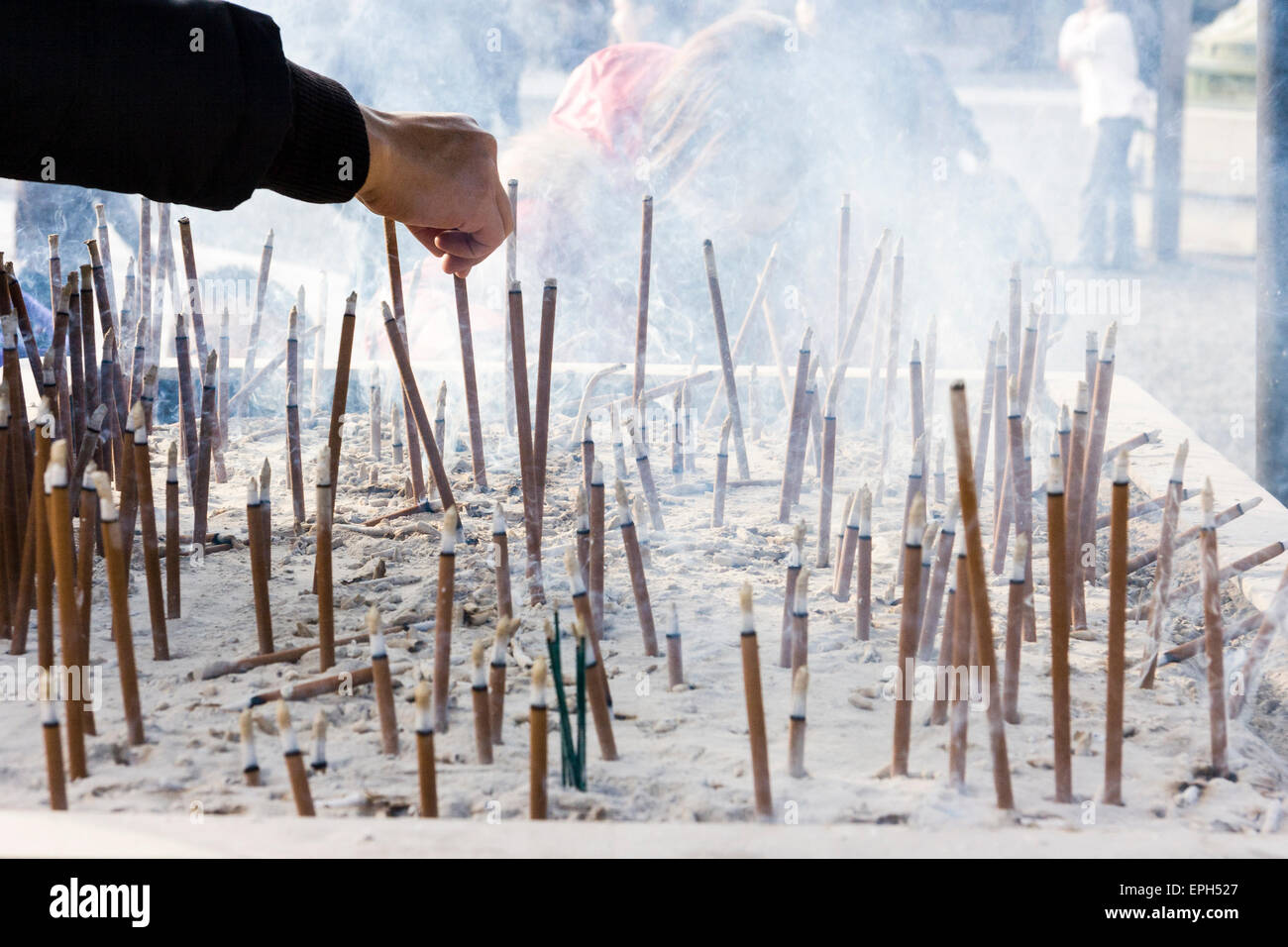 Chion-in Tempel in Kyoto. Hand über und placesing langen braunen Räucherstäbchen in Tablett von grauer Asche und andere Sticks schwelend. Stockfoto