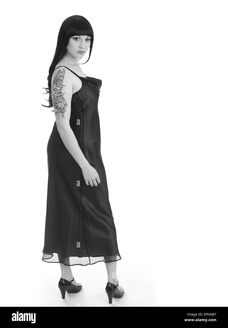 Schöne junge Frau zeigt ihr Schädel Tattoo ist auf dem oberen Arm während im Abendkleid Stockfoto