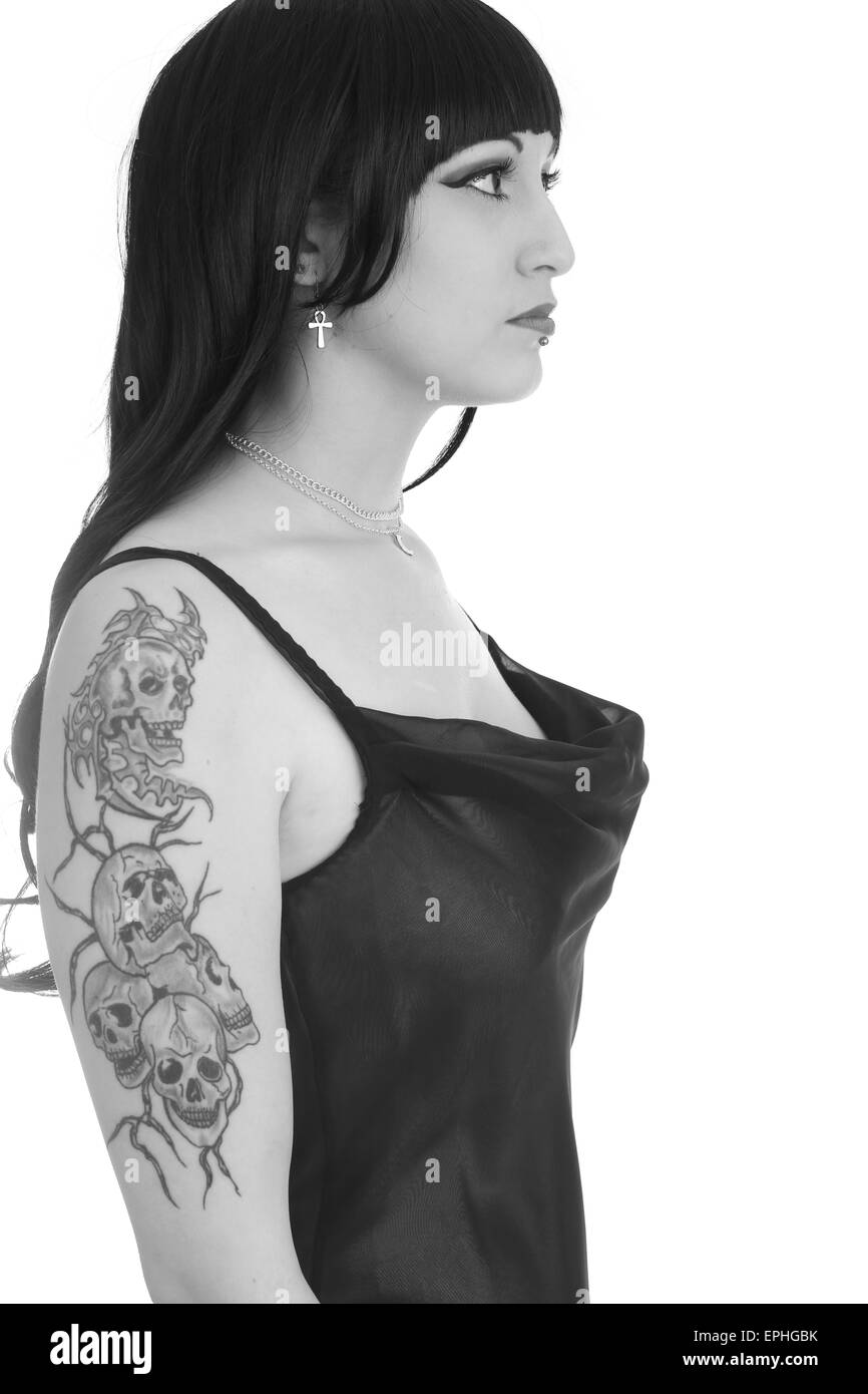 Schöne junge Frau zeigt ihr Schädel Tattoo ist auf dem oberen Arm während im Abendkleid Stockfoto
