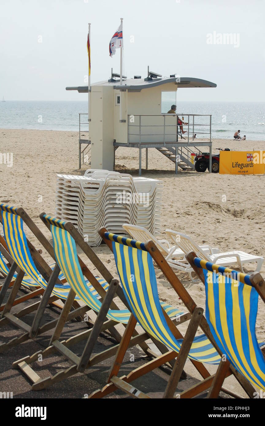 Strandkörbe an der Strandpromenade in Bournemouth in Dorset. Inzwischen sitzt ein Rettungsschwimmer in seinem Turm. Stockfoto