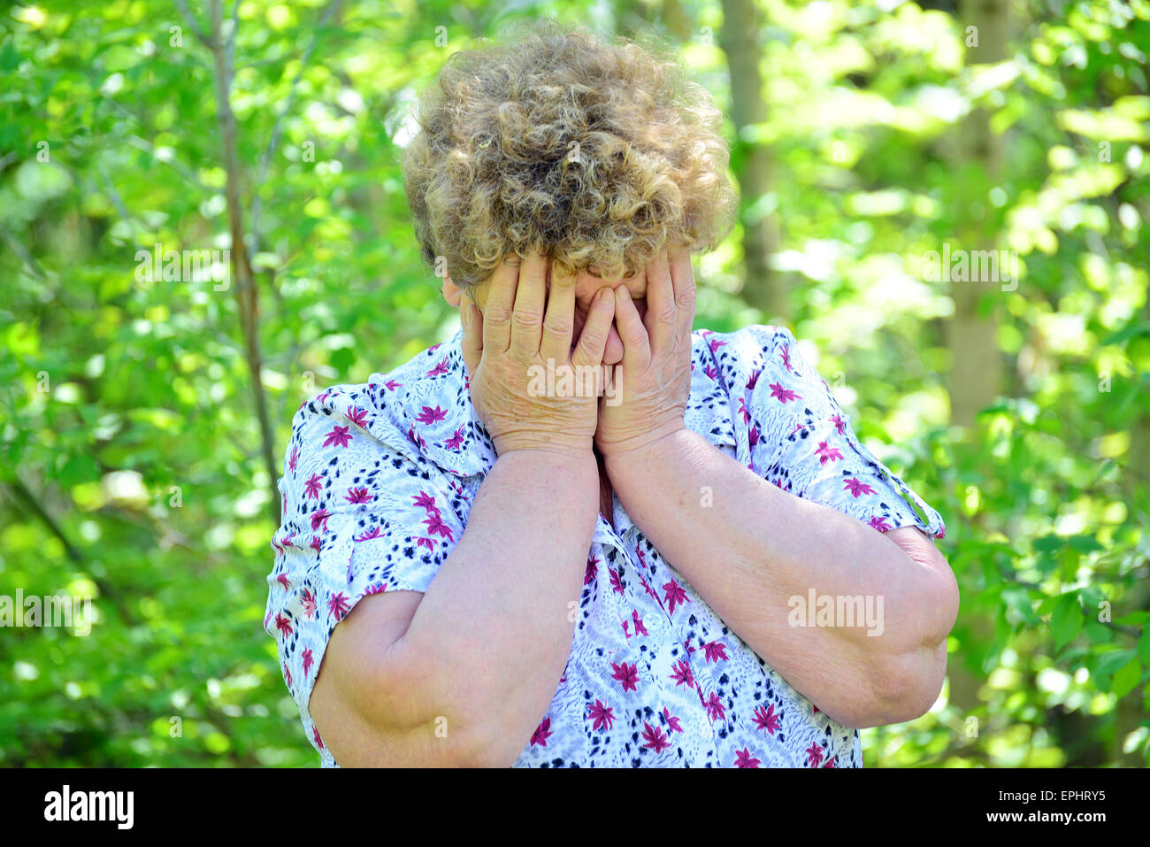 Reife Frau bedeckte ihr Gesicht mit ihren Händen in Trauer Stockfoto