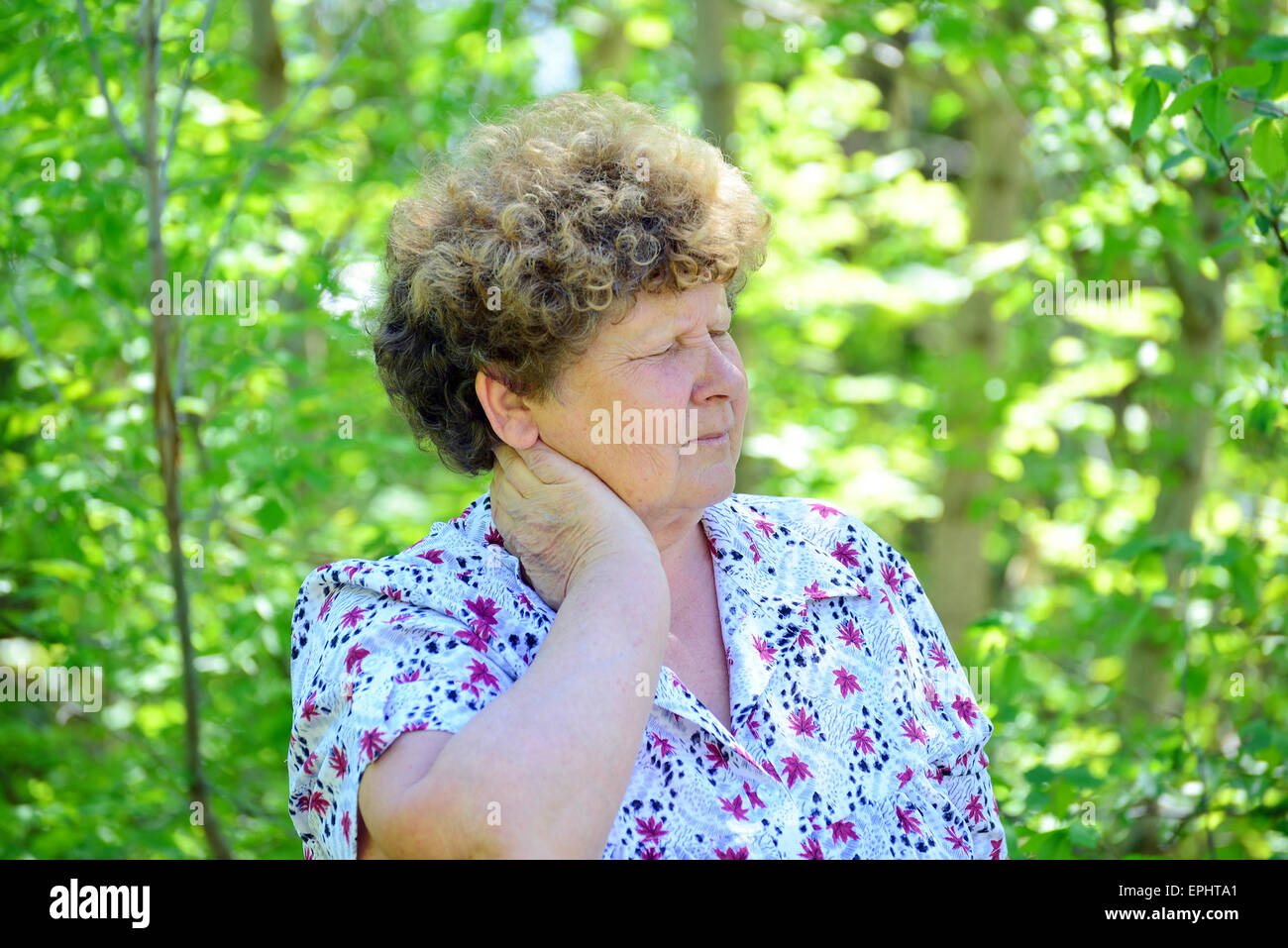 Reife Frau mit einem Schmerz im Nacken auf die Natur Stockfoto