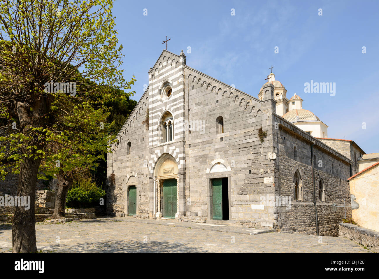 Ansicht des Baumes und kleinen Platz vor der mittelalterlichen Kirche San Lorenzo an einem sonnigen Frühlingstag, Portovenere, Italien Stockfoto