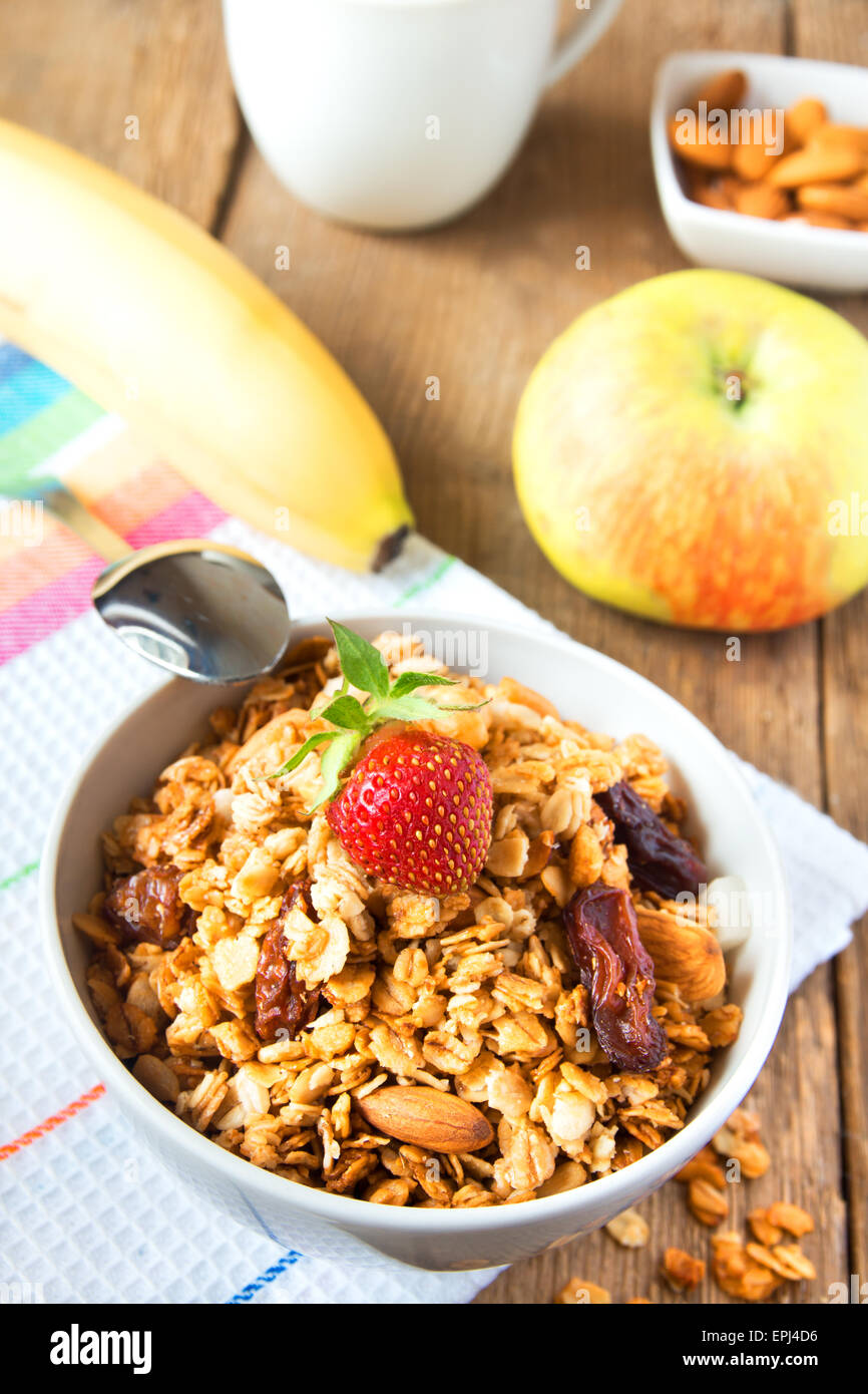 Gesundes Frühstück mit Vollkorn-Müsli, Früchten, Nüssen und Milch über rustikalen Holztisch Stockfoto
