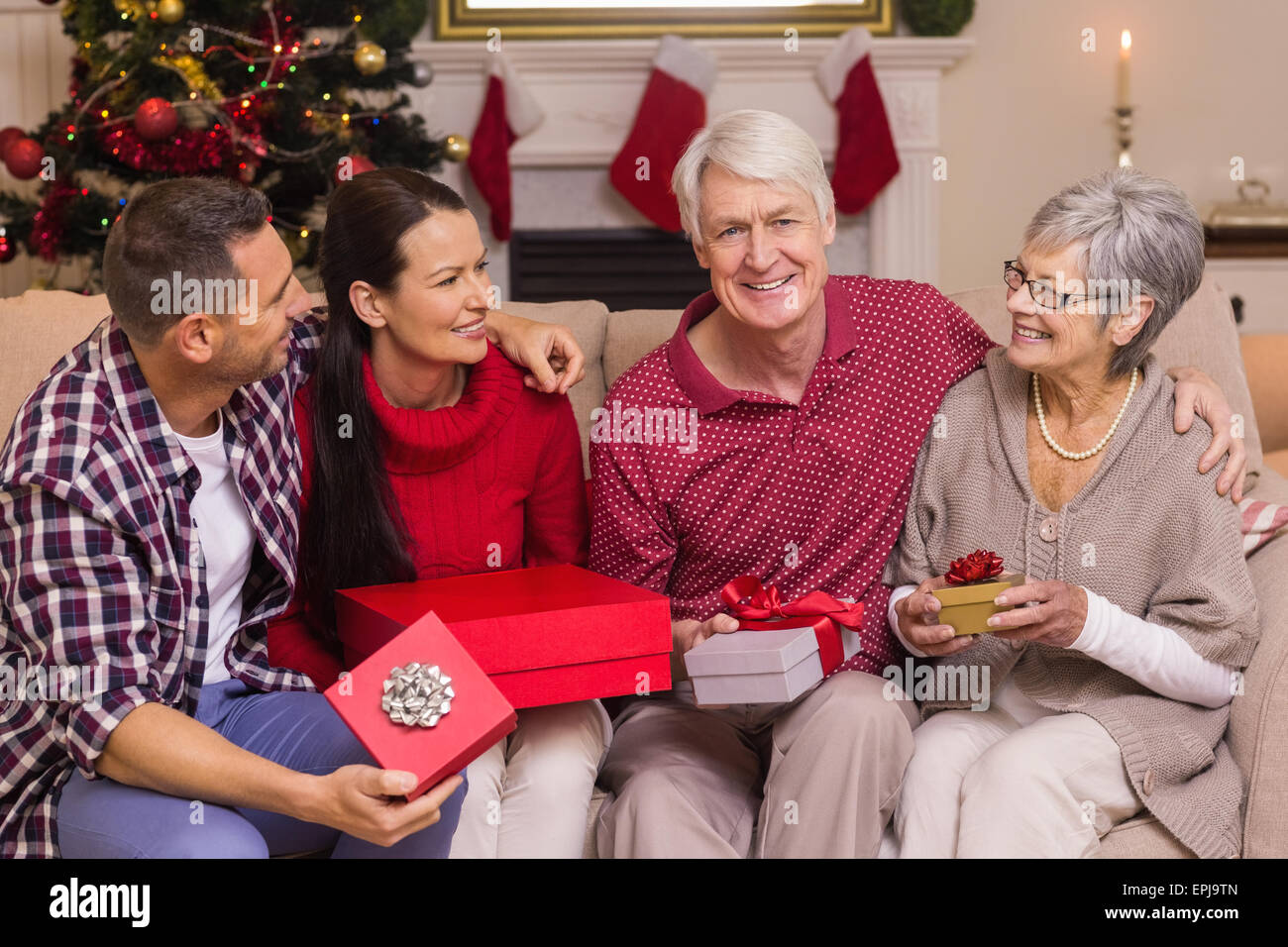 Lächelnde Familienholding Geschenk auf sofa Stockfoto