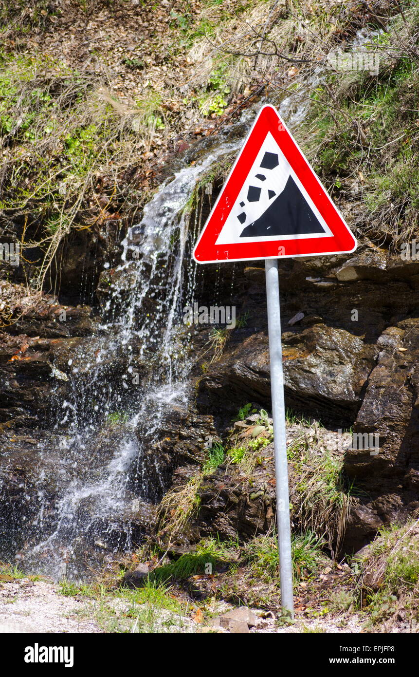 Kleiner Wasserfall läuft hinter einem Erdrutsch Zeichen im freien Stockfoto