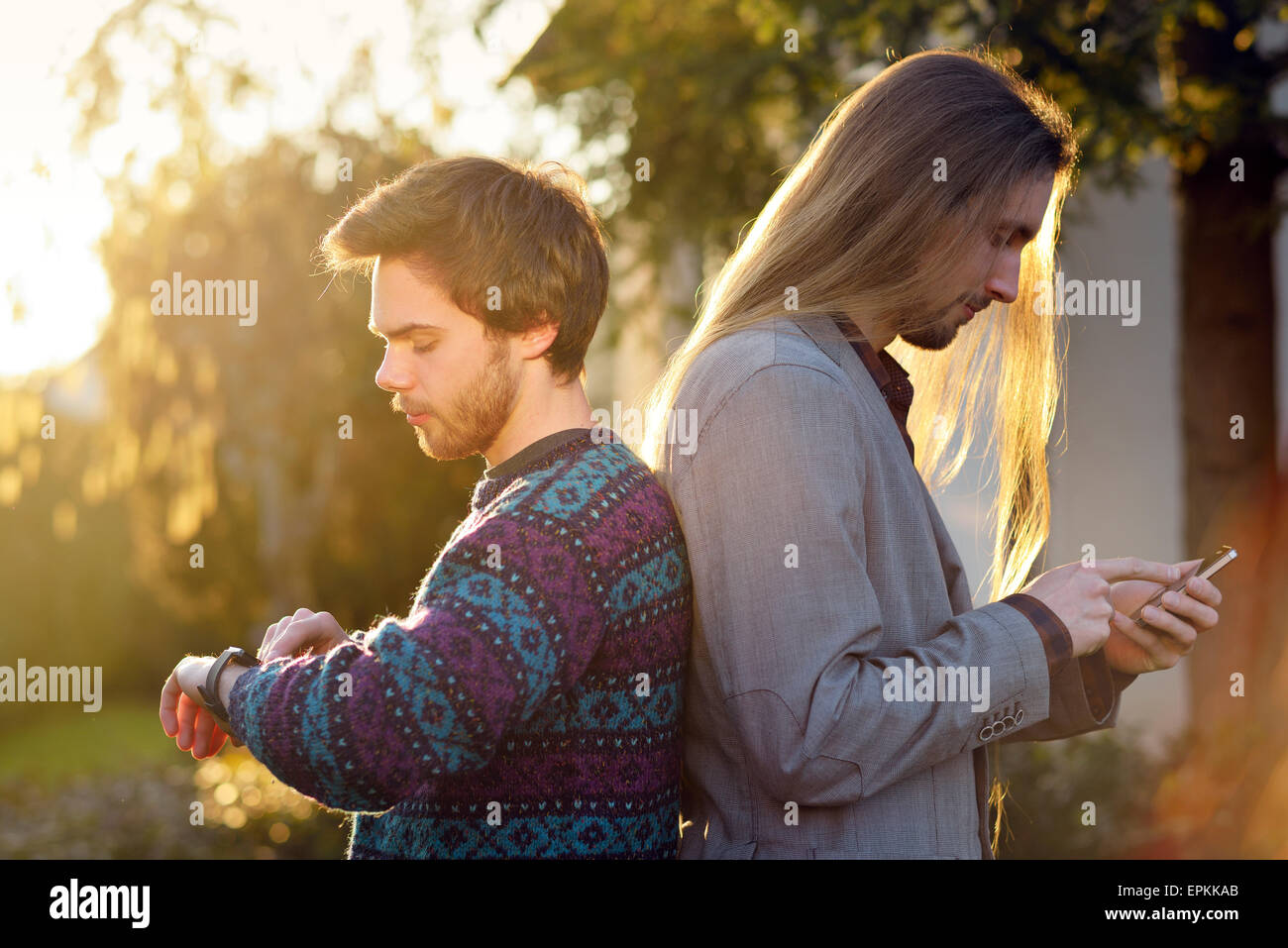 Zwei Hipster Rücken an Rücken mit Smartwatch und smartphone Stockfoto