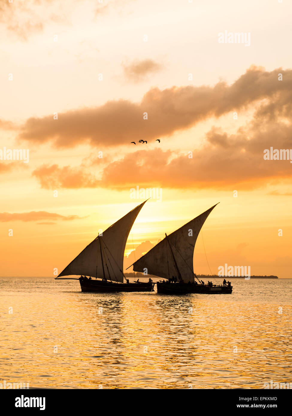 Zwei traditionelle tansanische Dhow Boote auf dem offenen Meer am Indischen Ozean in der Nähe von Stone Town auf Sansibar, bei orange Sonnenuntergang. Stockfoto
