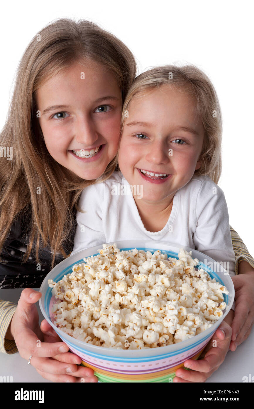 Porträt von zwei blonden Schwestern mit einer Schüssel Popcorn auf weißem Hintergrund Stockfoto