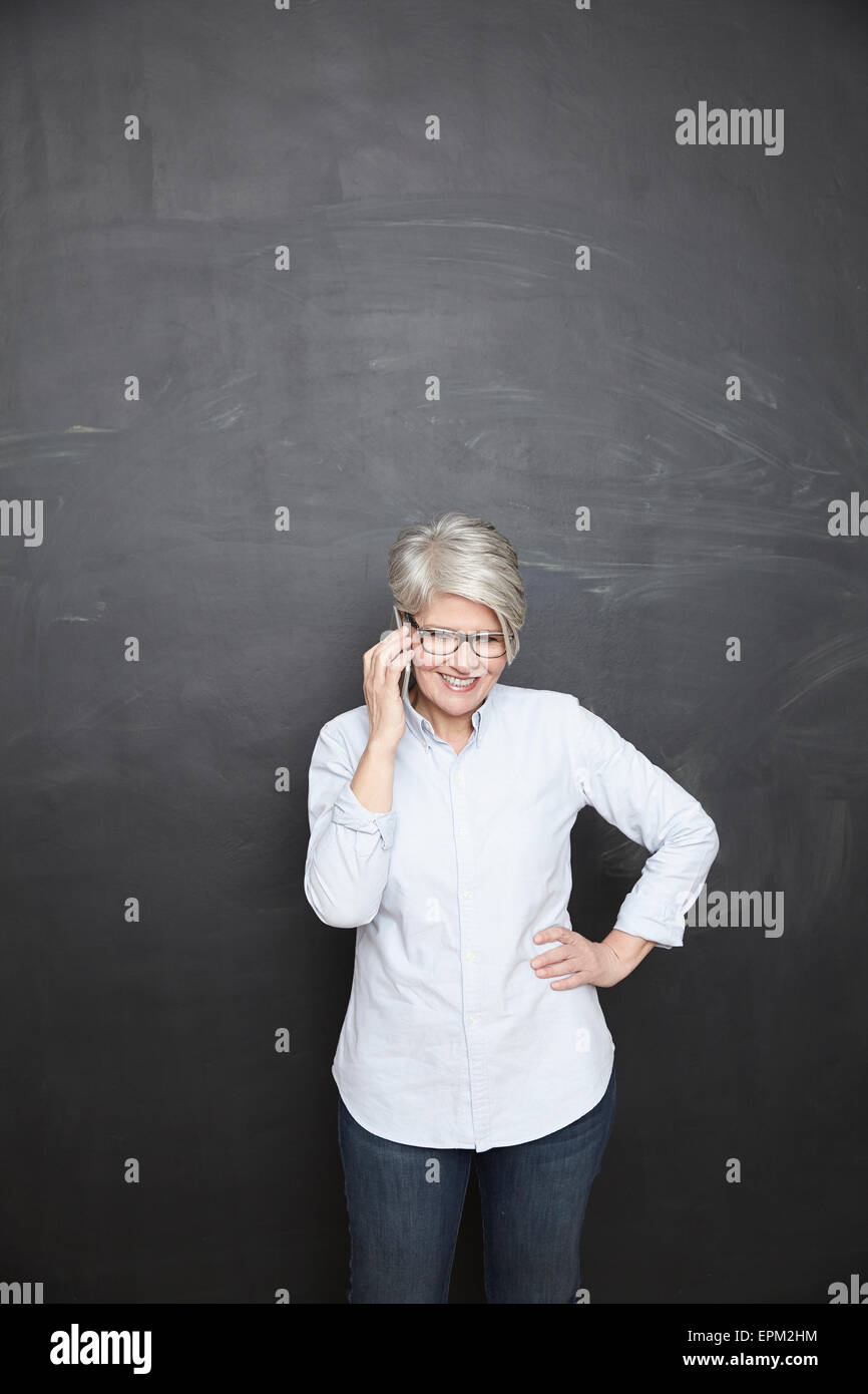 Reife Frau an der Tafel auf Handy Stockfoto