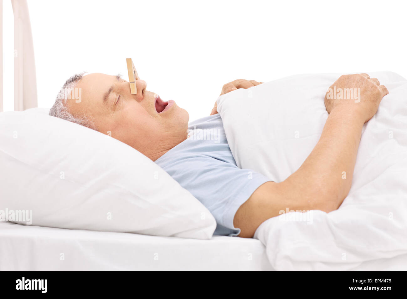 Senior in einem Bett schlafen und Schnarchen mit einer Wäscheklammer stecken auf der Nase isoliert auf weißem Hintergrund Stockfoto