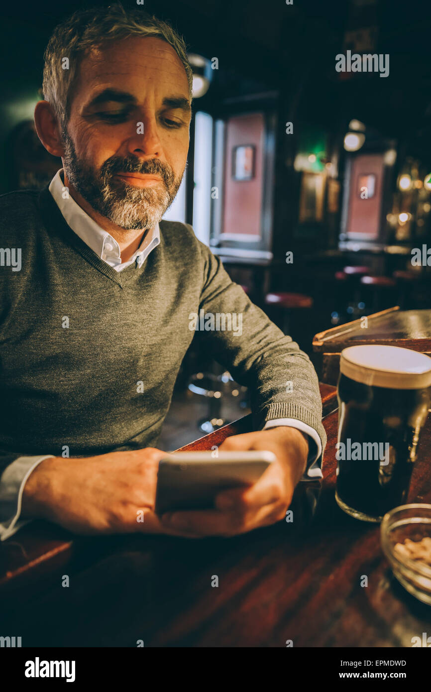 Porträt des Menschen sitzen an der Theke einer Kneipe mit smartphone Stockfoto
