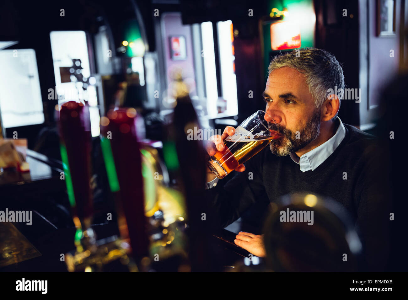 Mann sitzt am Schalter einer Kneipe Bier trinken Stockfoto