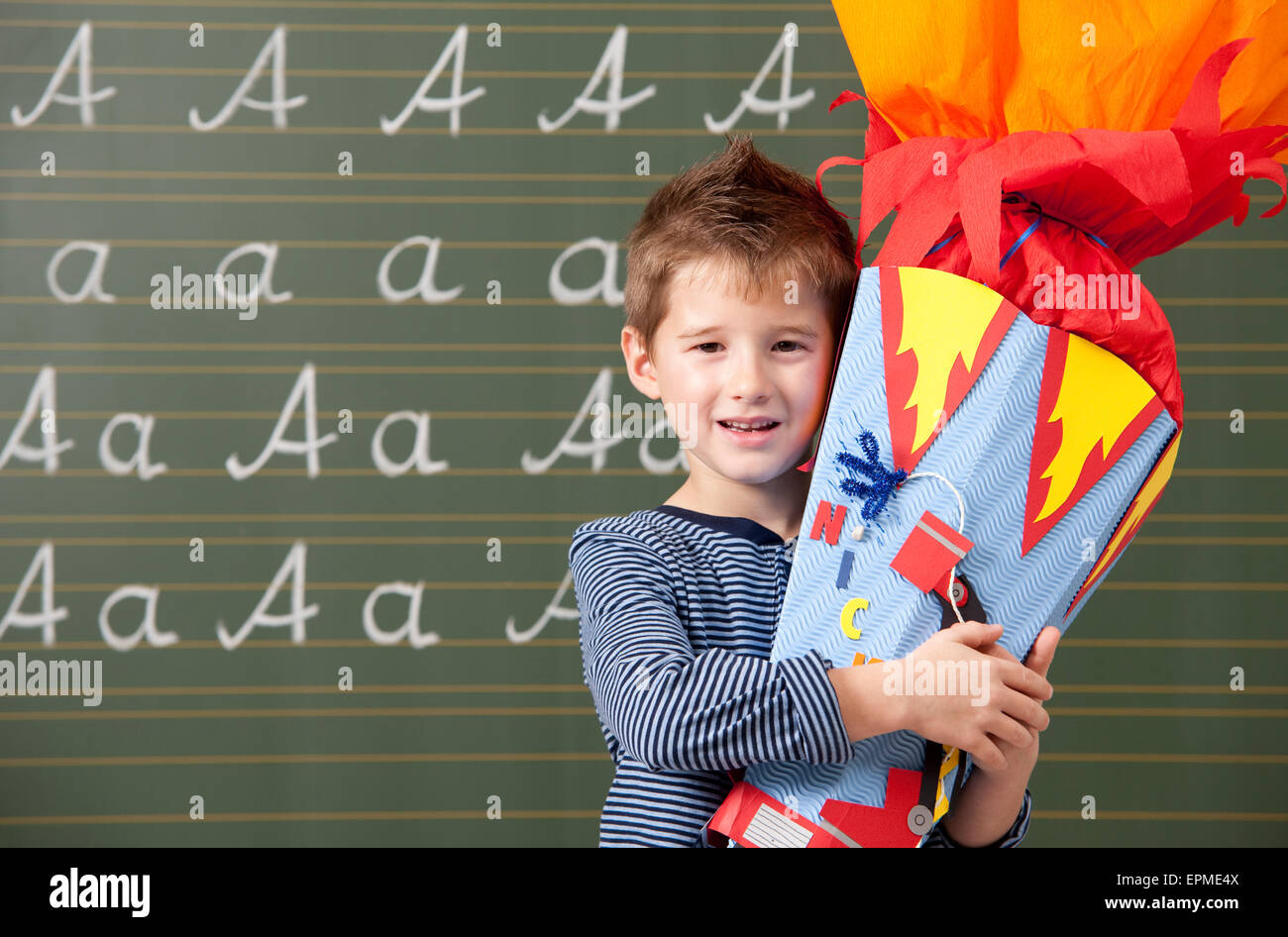 Fröhlicher Junge mit Schule Kegel an der Tafel Stockfoto