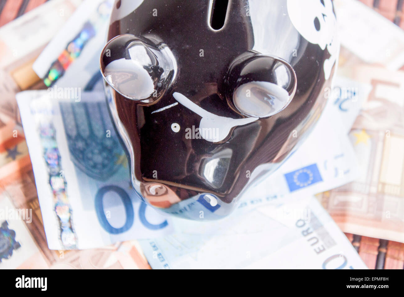 Schwarzes Sparschwein auf einen Haufen Geld Stockfoto