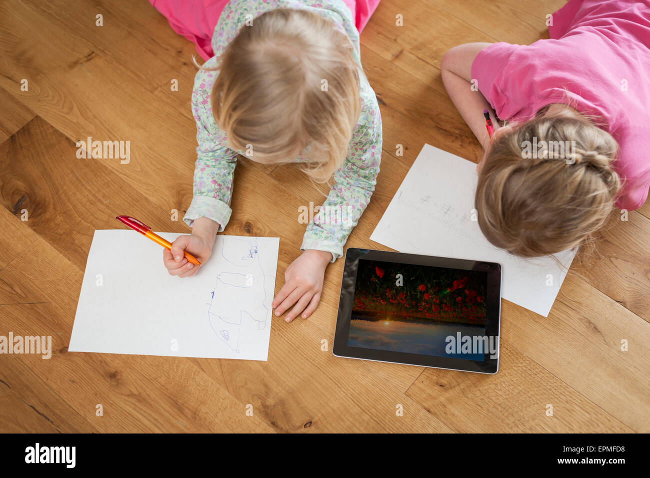 Zwei Schwestern mit digital-Tablette und Blatt Papier auf Boden Stockfoto