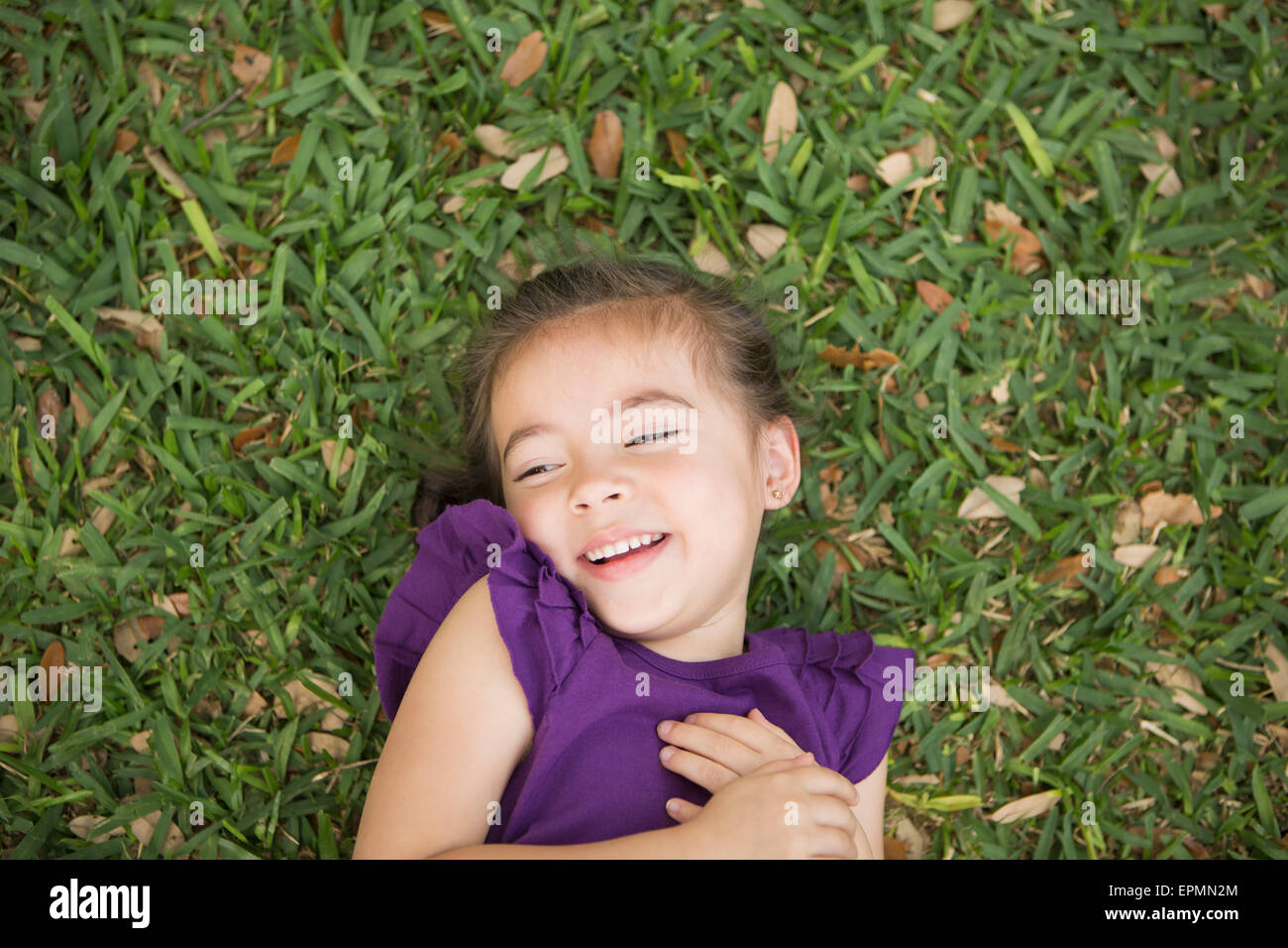 Ein Kind auf dem Rücken im Gras liegend. Stockfoto