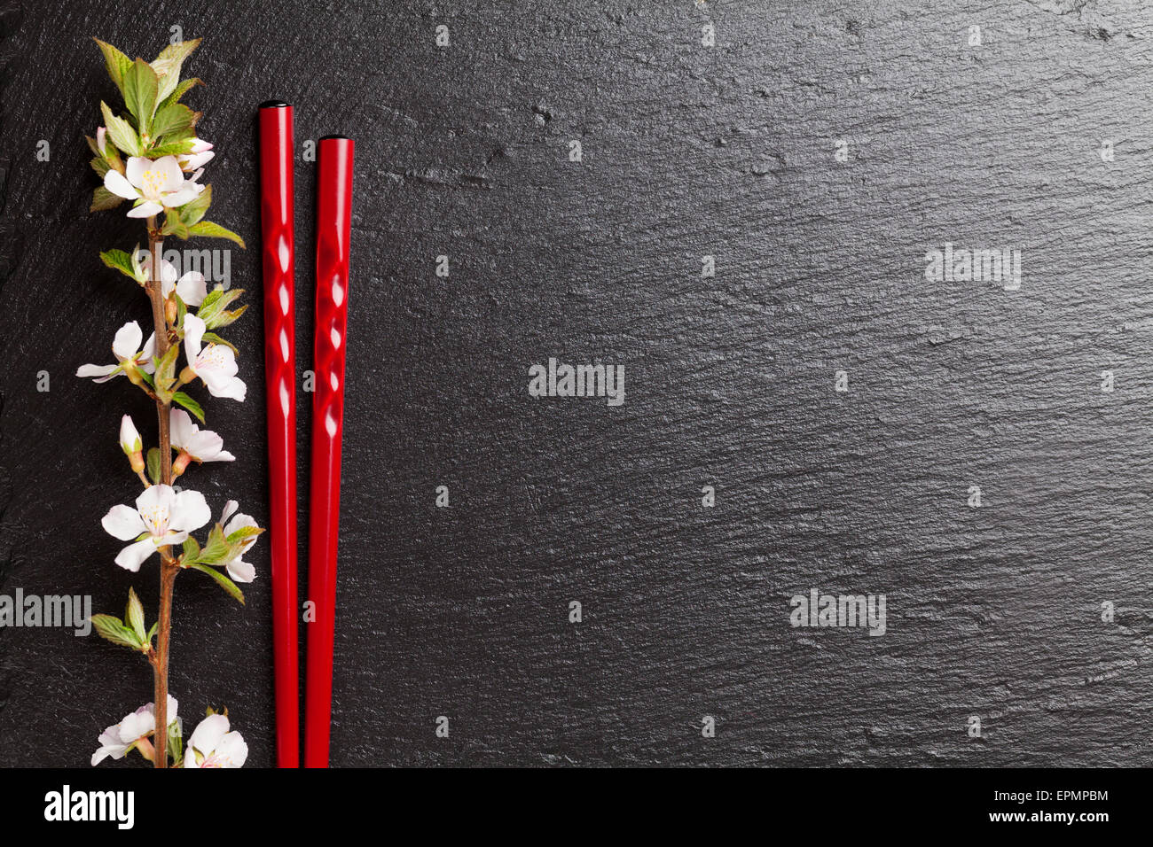 Japanische Sushi-Stäbchen und Sakura Blüte auf schwarzem Stein. Draufsicht mit Textfreiraum Stockfoto