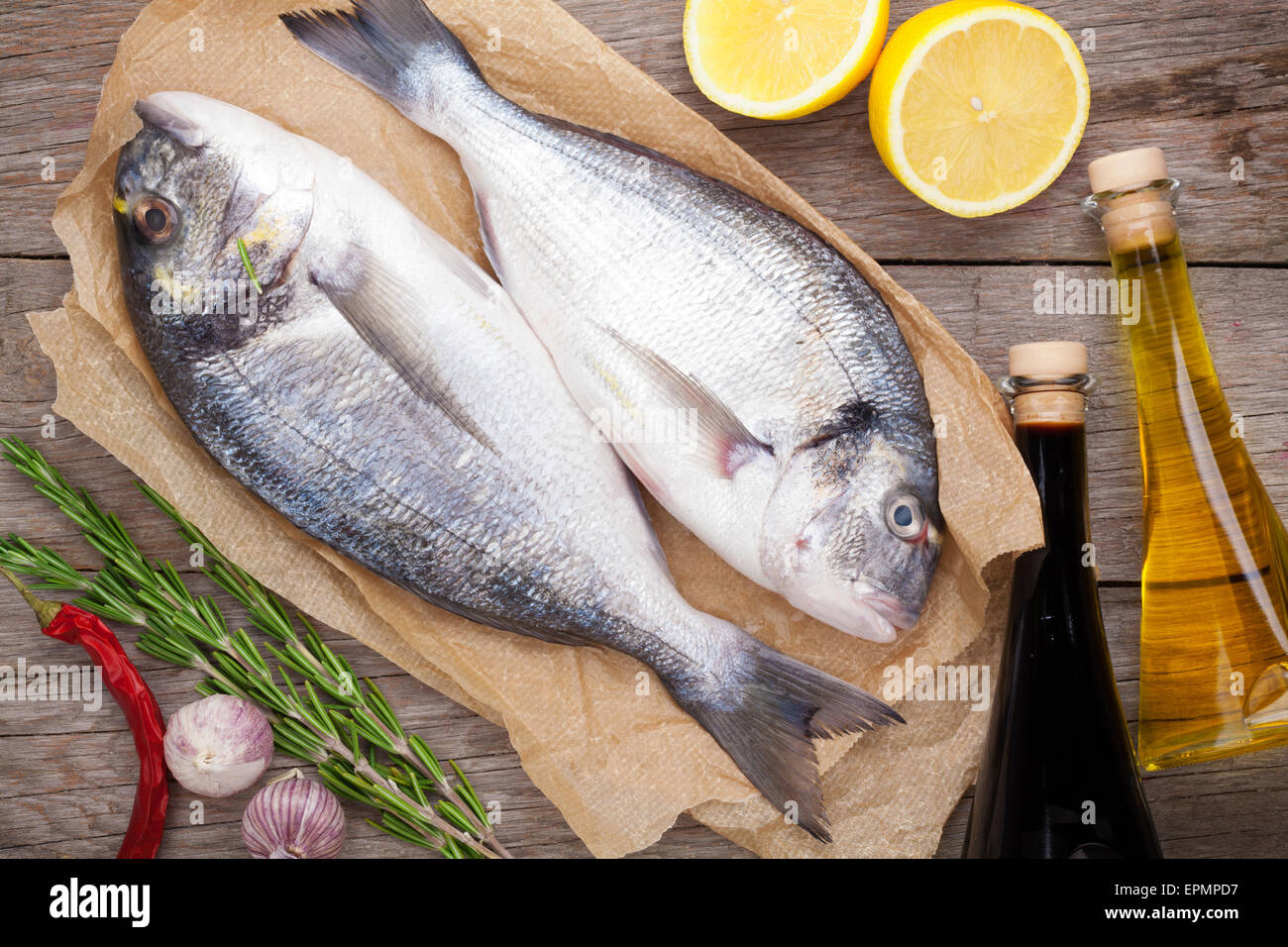 Dorado Frischfisch Kochen mit Gewürzen und Zutaten auf Holztisch Stockfoto