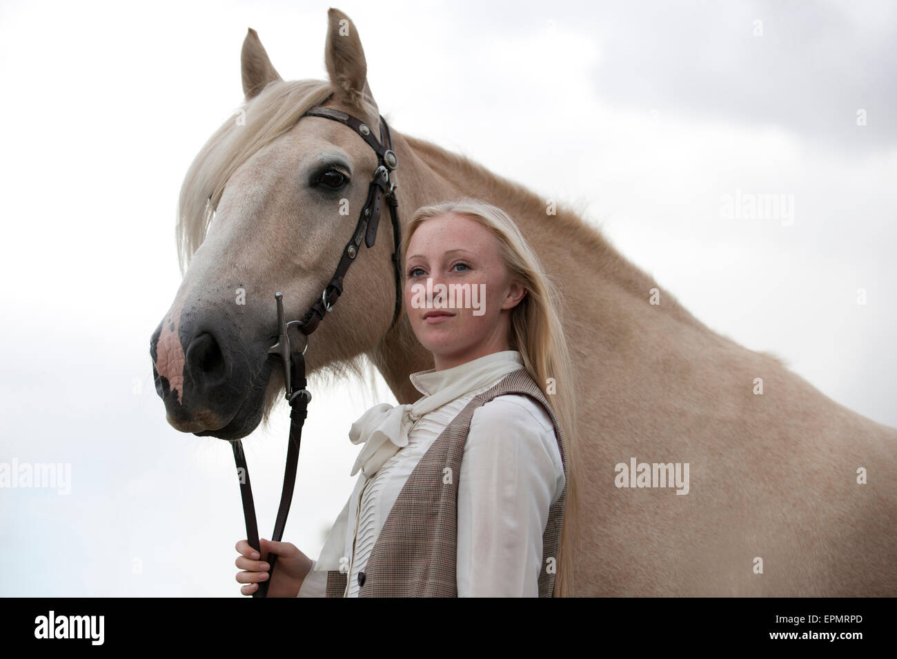 Eine junge Frau hält ein Palomino-Pferd Stockfoto