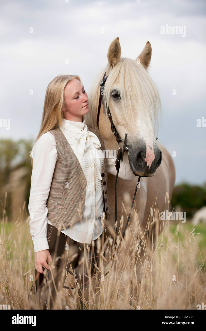 Eine junge Frau hält ein Palomino-Pferd Stockfoto