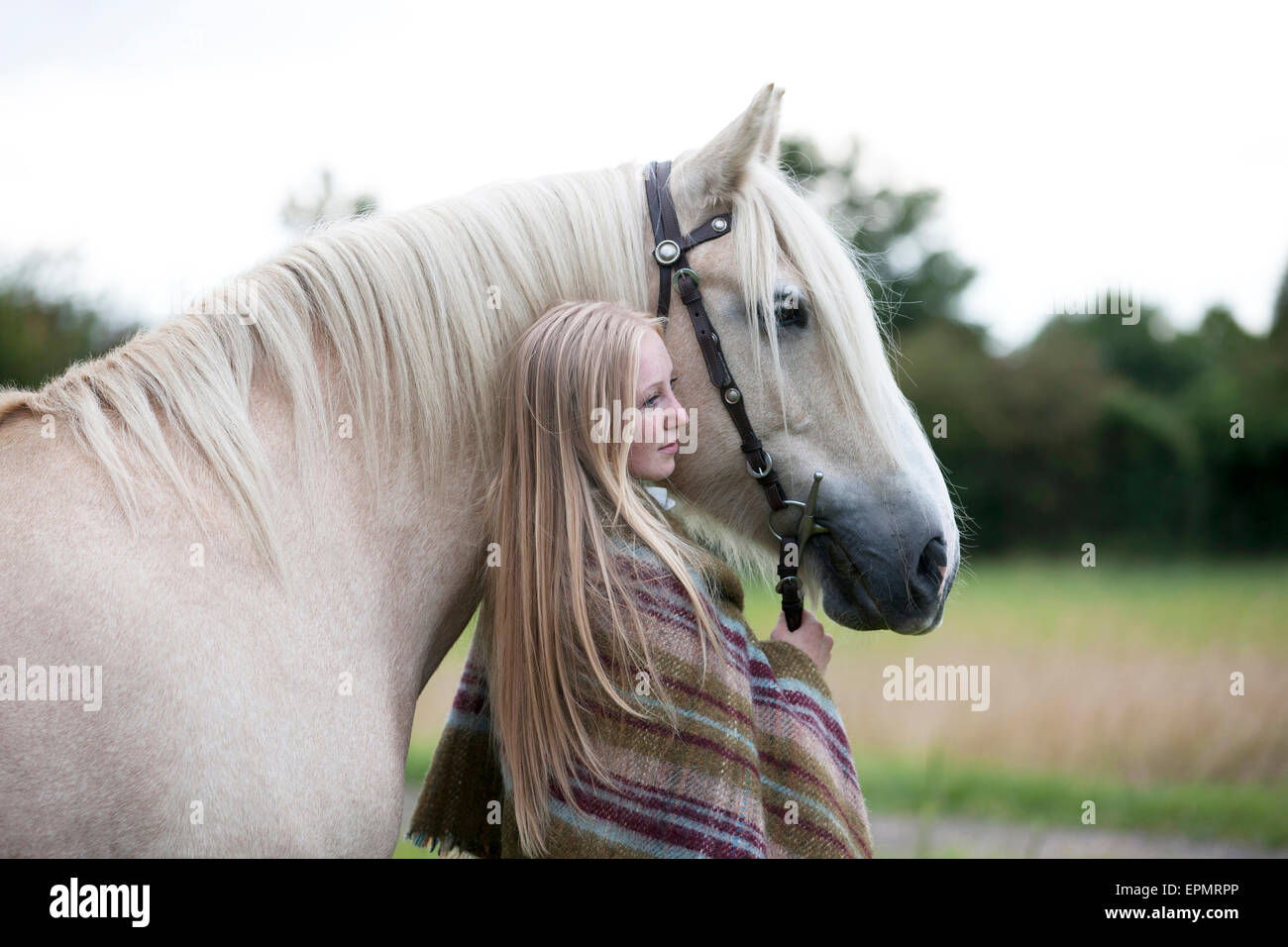 Eine junge Frau stand neben einem Palomino-Pferd Stockfoto