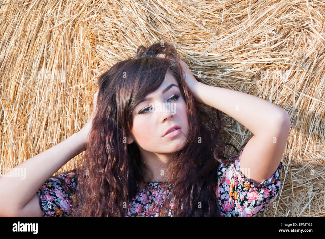 Sommerportrait eines schönen Landmädchen auf einem Hintergrund aus Stroh. Stockfoto