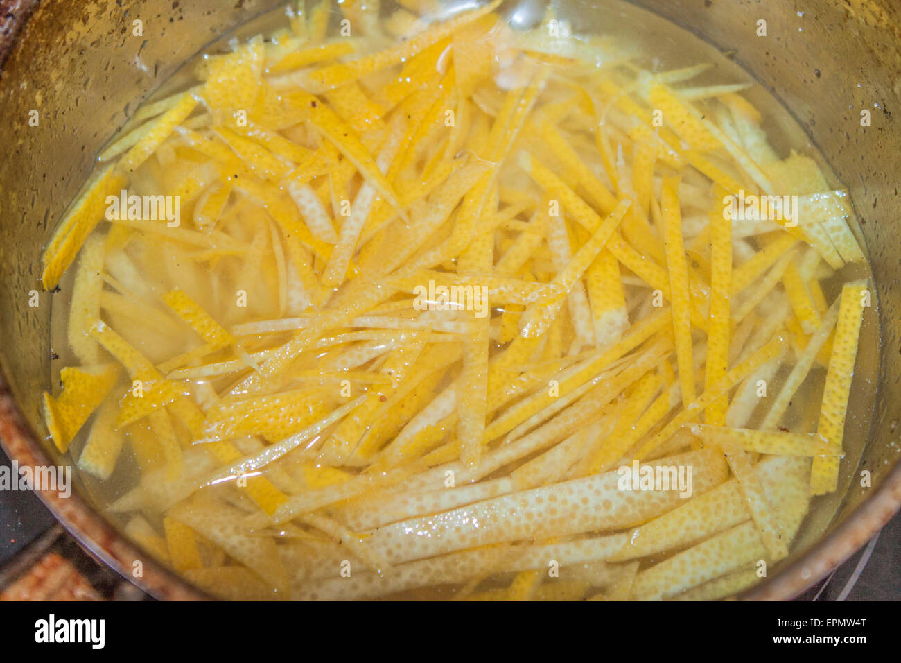 Kochende gelbe Zitronenschale in Zuckersirup Stockfoto