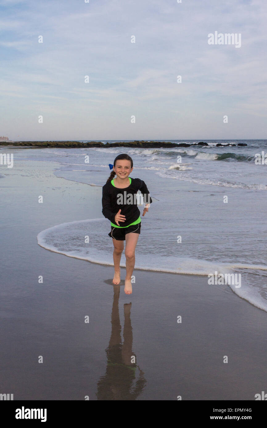 Ein sportliches zehn Jahres altes Mädchen übt am Strand in Long Beach, Long Island, New York. Sie genießt laufen und Fußball. Stockfoto