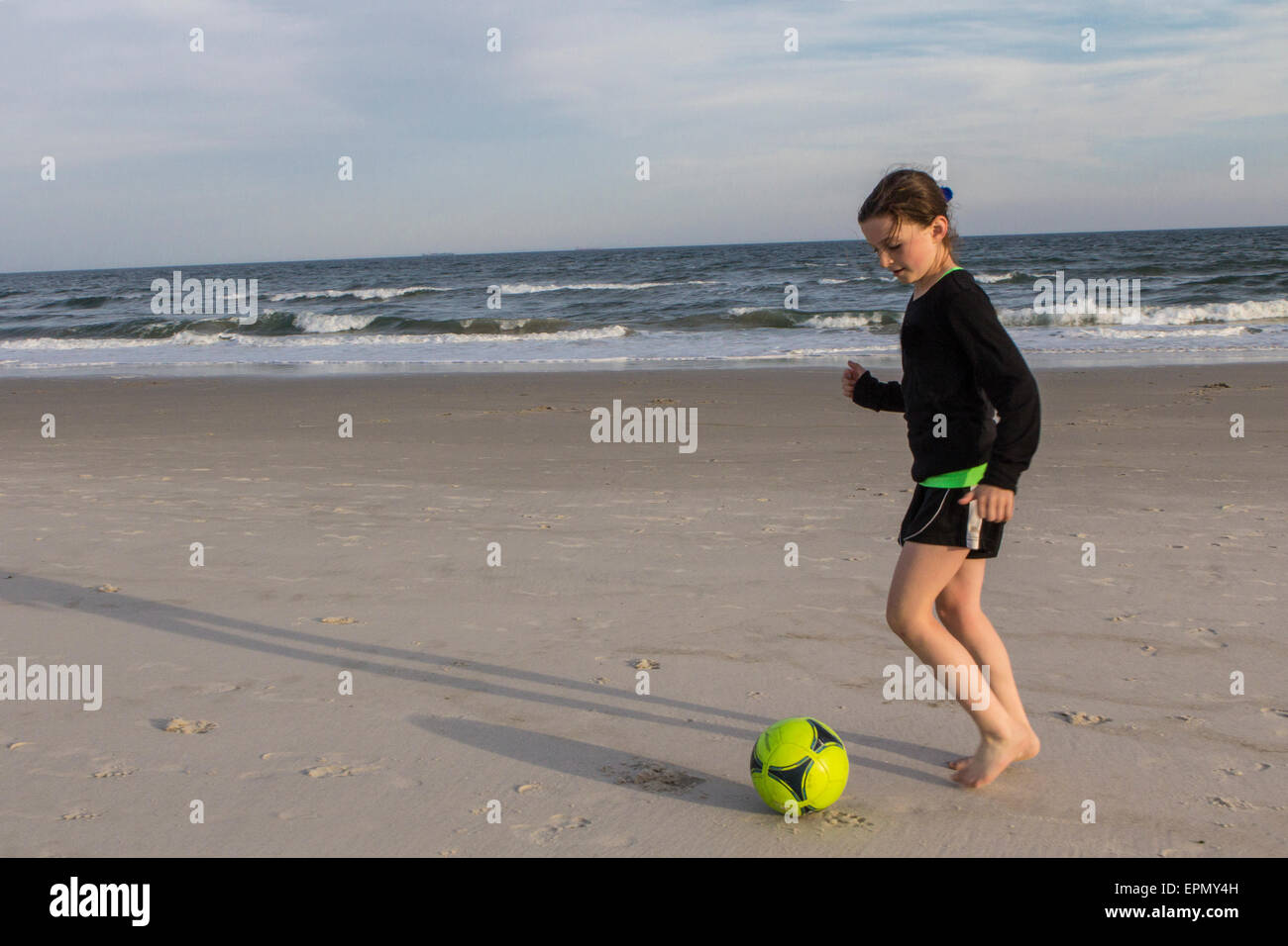 Ein sportliches zehn Jahres altes Mädchen übt am Strand in Long Beach, Long Island, New York. Sie genießt laufen und Fußball. Stockfoto