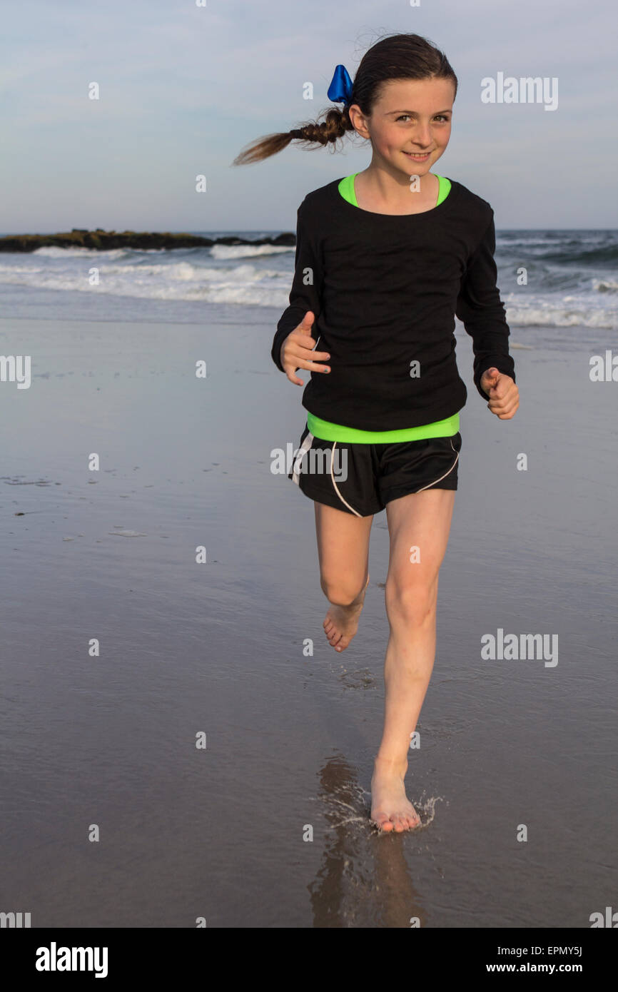 Ein sportliches zehn Jahres altes Mädchen läuft am Strand in Long Beach, New York. Sie beteiligt sich an lokalen Laufveranstaltungen und liebt Bewegung. Stockfoto