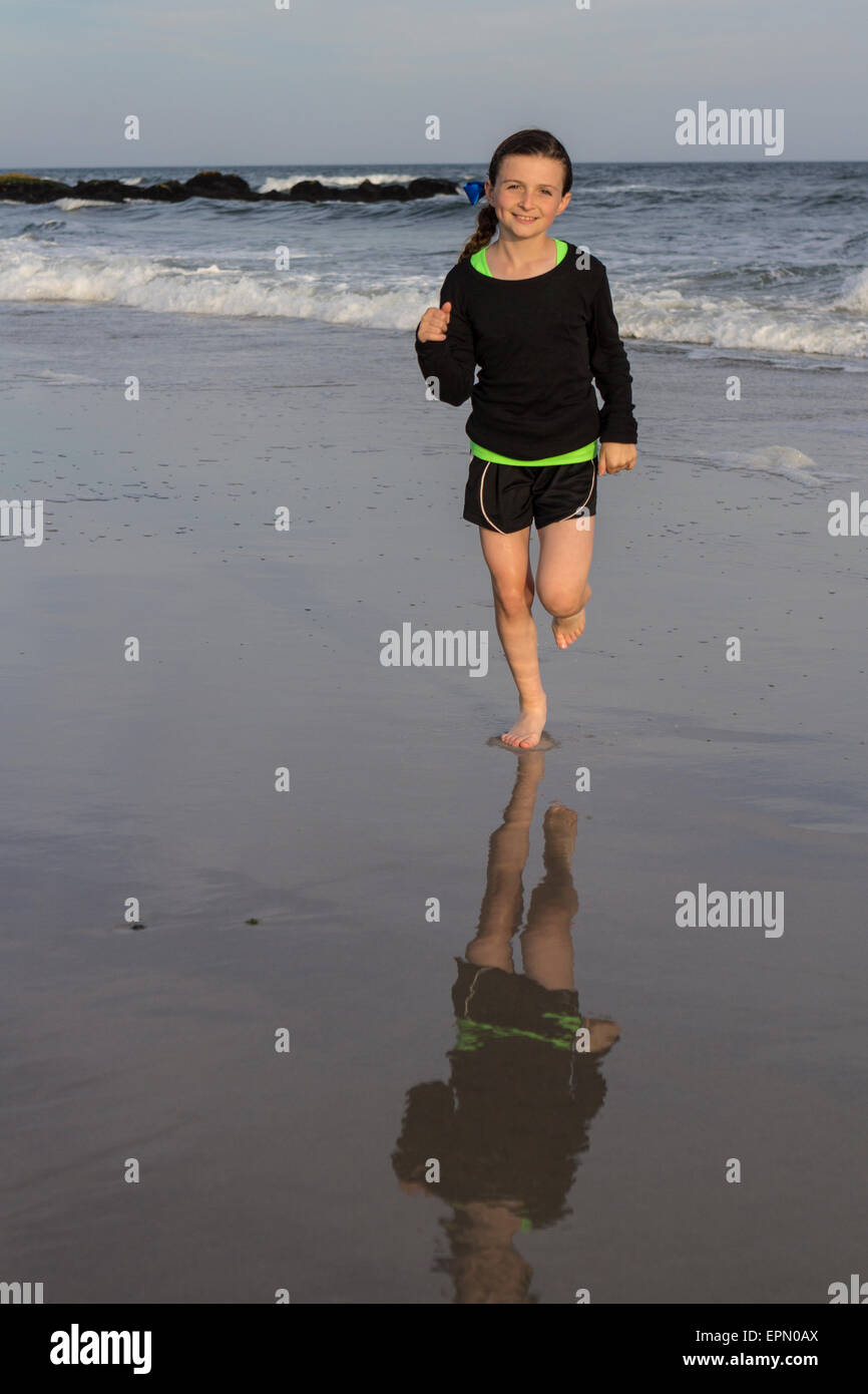 Ein sportliches zehn Jahres altes Mädchen läuft am Strand in Long Beach, New York. Sie beteiligt sich an lokalen Laufveranstaltungen und liebt Bewegung. Stockfoto