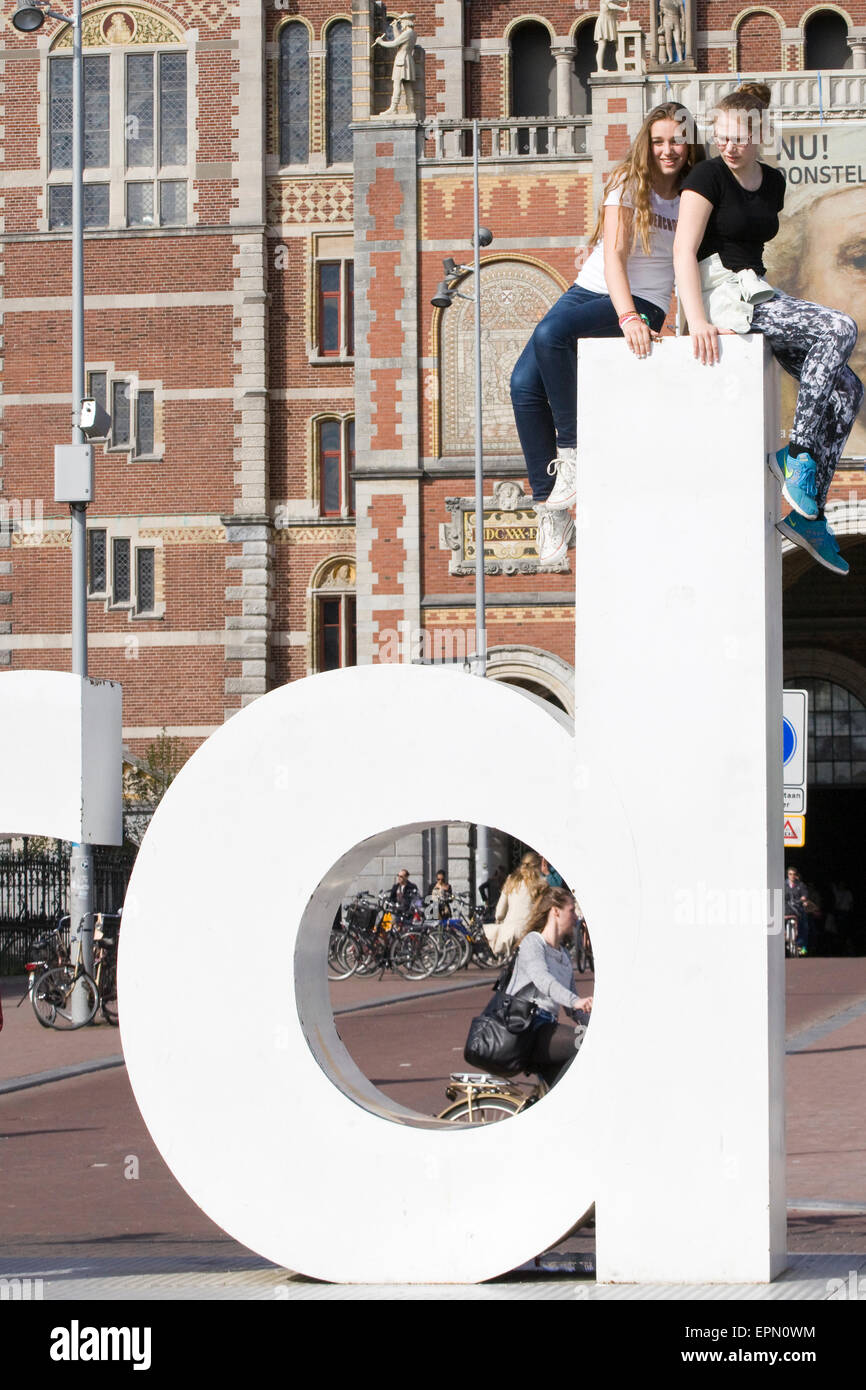 Zwei junge Mädchen sitzen auf der riesigen D auf der Amsterdam-Skulptur in den Niederlanden Stockfoto