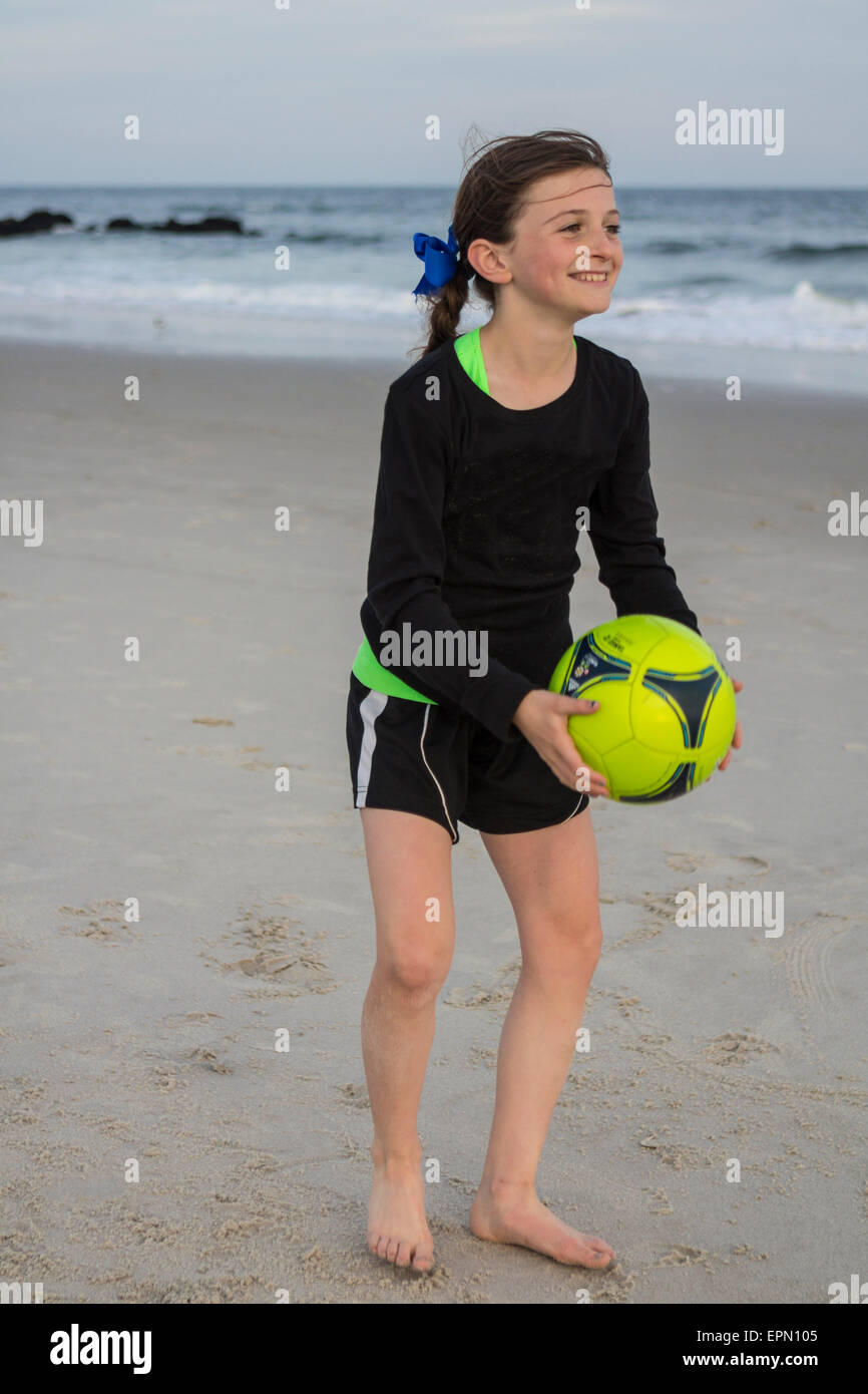 Ein Zehn Jahres altes Mädchen spielt mit einem Fußball am Meer entlang in Long Beach, New York. Sie spielt Fußball auf ihrer Schule-Team. Stockfoto