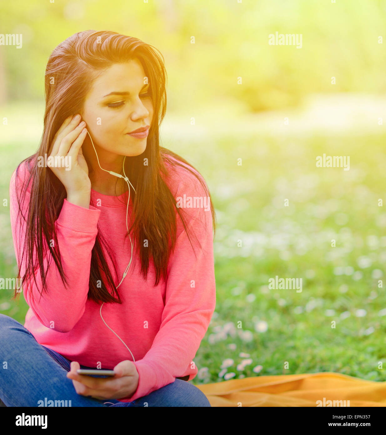 Weibliche Studentin draußen im Park Musik über Kopfhörer hören Stockfoto